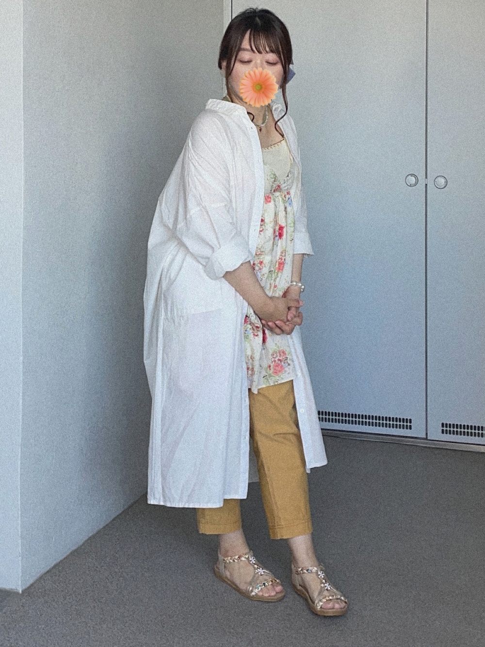 イエロー系のチノパンツ、ホワイト系のシャツワンピース、ベージュ系のチュニックを着用したレディースの夏コーディネートの2枚目の写真