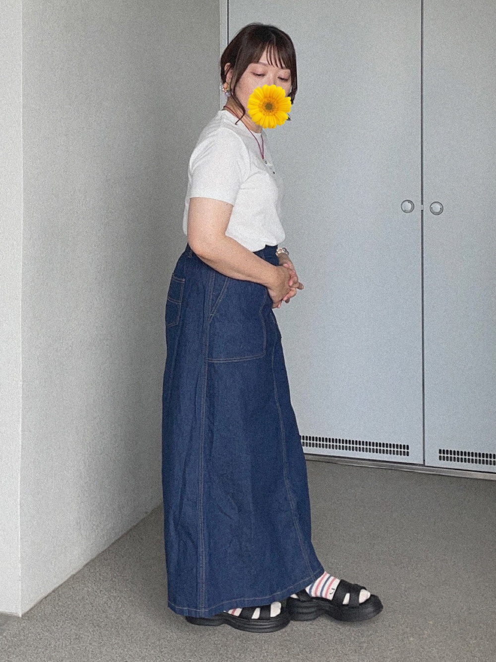 ホワイト系のTシャツ/カットソー、ブルー系のデニムスカート、ブラック系のサンダルを着用したレディースの秋コーディネートの3枚目の写真
