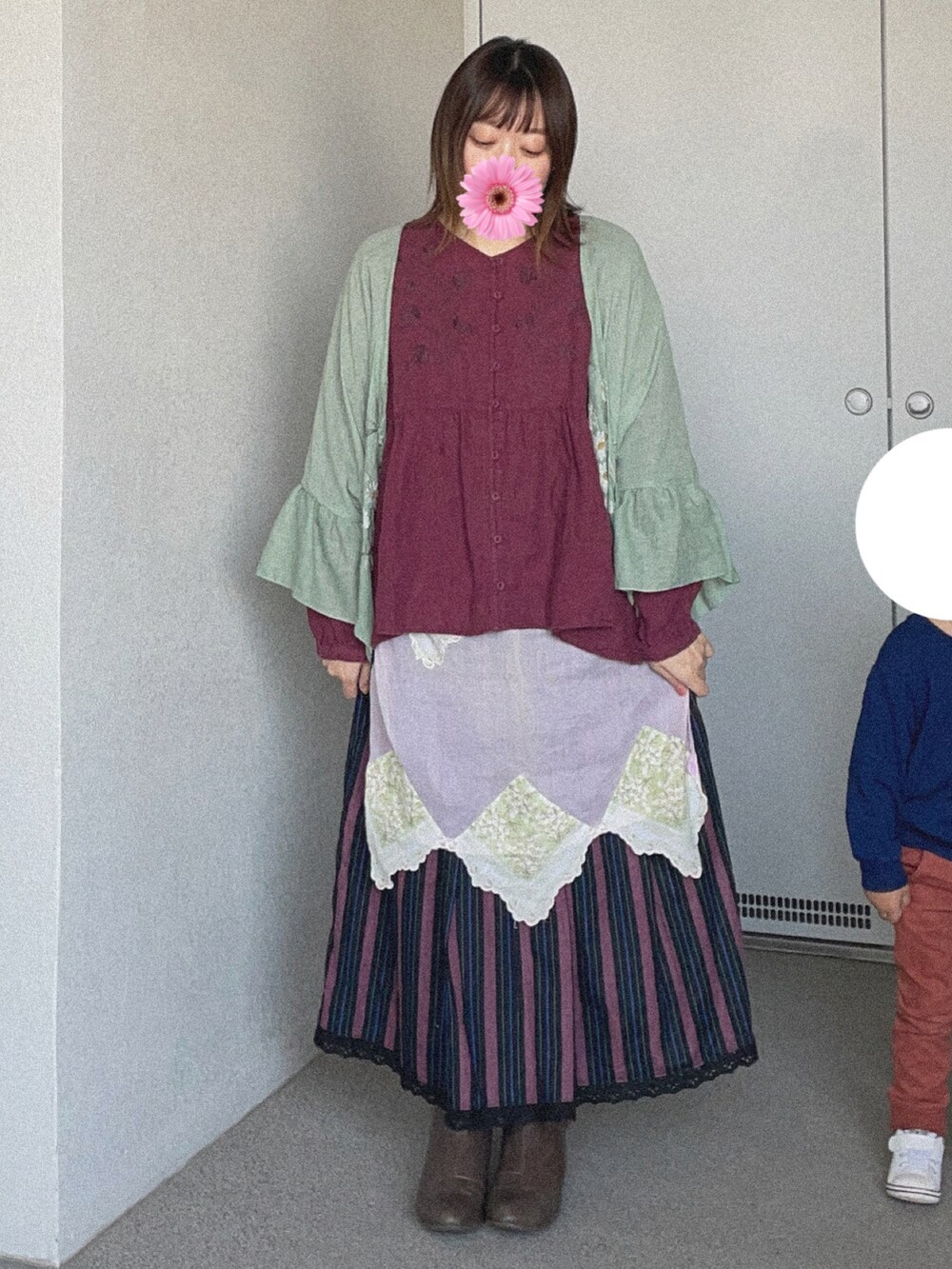 レッド系のTシャツ/カットソー、グリーン系のカーディガン/ボレロ、パープル系のスカートを着用したレディースの冬コーディネートの2枚目の写真