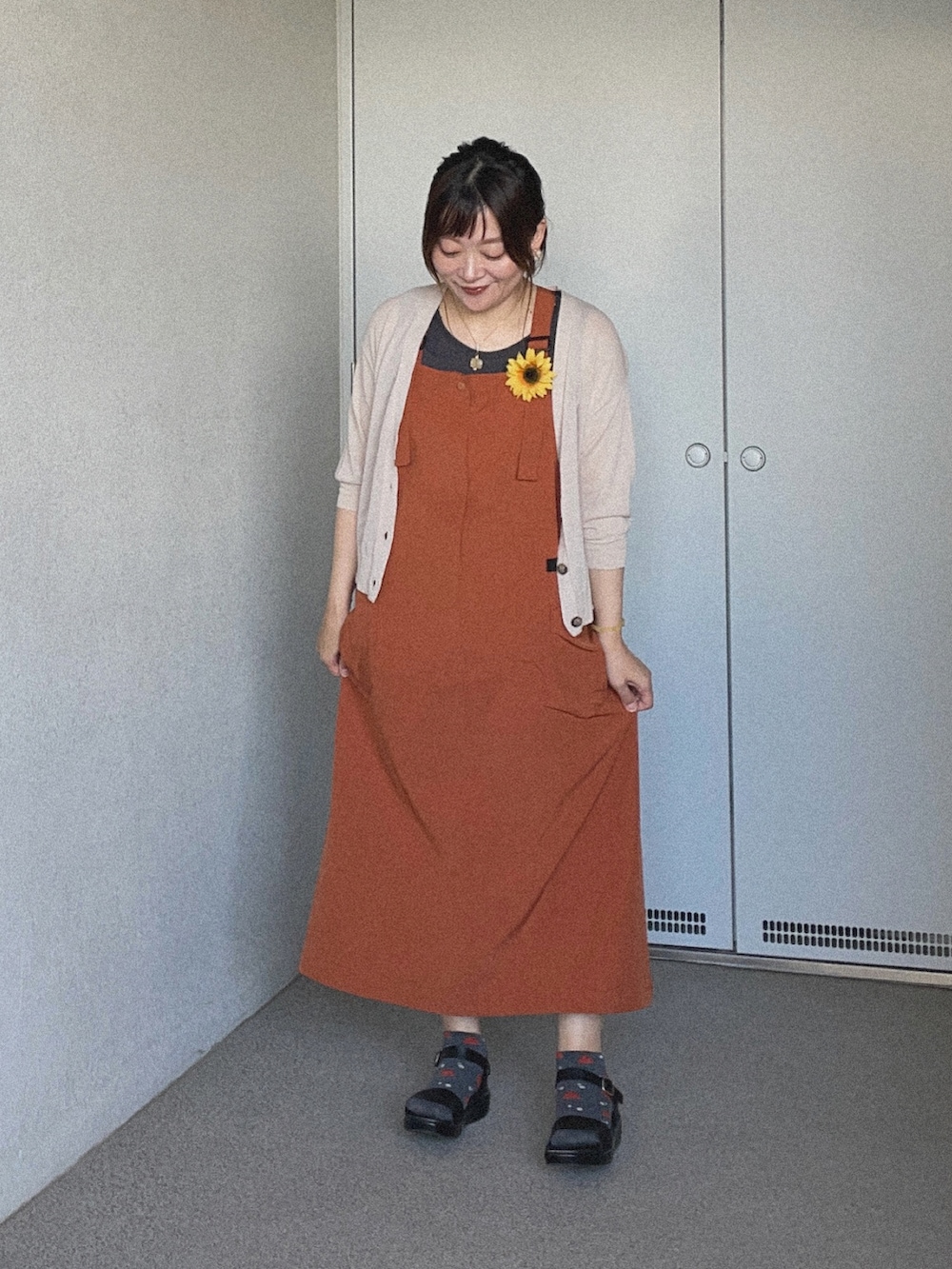 ブラック系のタンクトップ、オレンジ系のジャンパースカート、グレー系のカーディガン/ボレロを着用したレディースの夏コーディネートの2枚目の写真