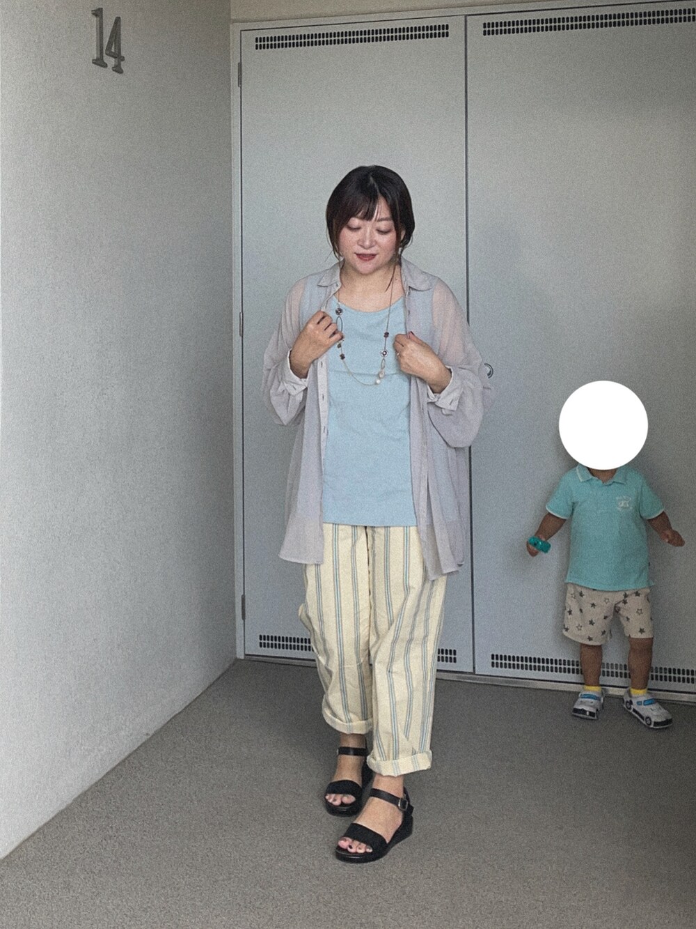 ブルー系のタンクトップ、ベージュ系のチノパンツ、ブラック系のサンダルを着用したレディースの夏コーディネートの2枚目の写真