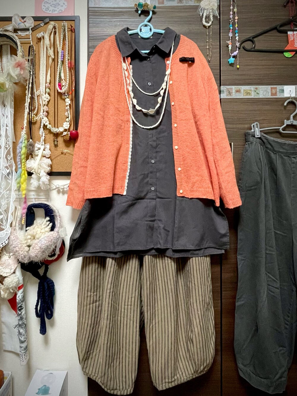 ブラック系のシャツ/ブラウス、オレンジ系のカーディガン/ボレロ、ブラウン系のチノパンツを着用したレディースの冬コーディネートの5枚目の写真