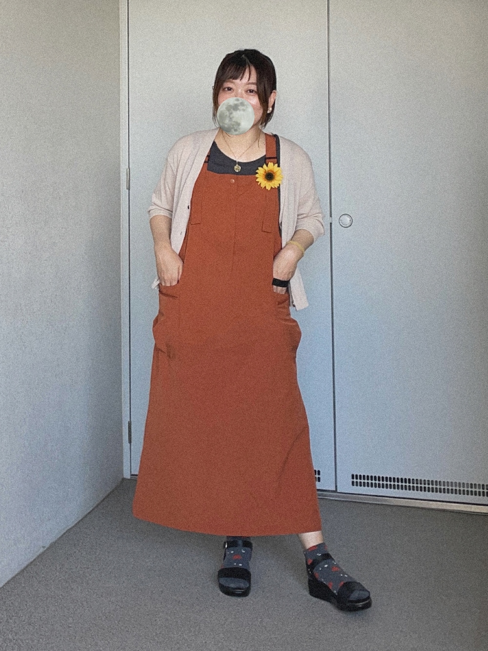 ブラック系のタンクトップ、オレンジ系のジャンパースカート、グレー系のカーディガン/ボレロを着用したレディースの夏コーディネートの3枚目の写真