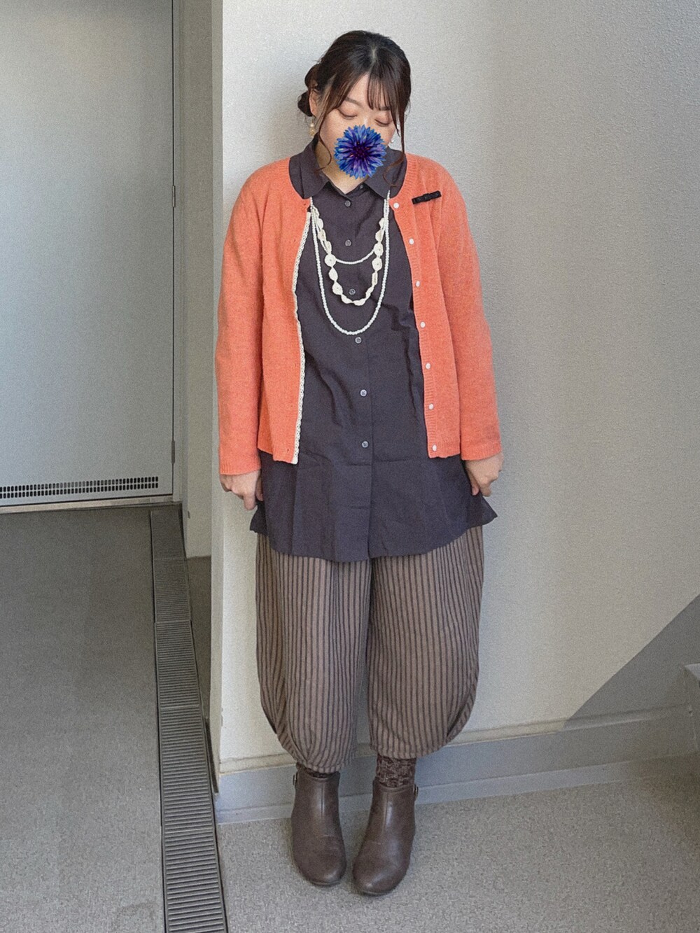 ブラック系のシャツ/ブラウス、オレンジ系のカーディガン/ボレロ、ブラウン系のチノパンツを着用したレディースの冬コーディネートの3枚目の写真