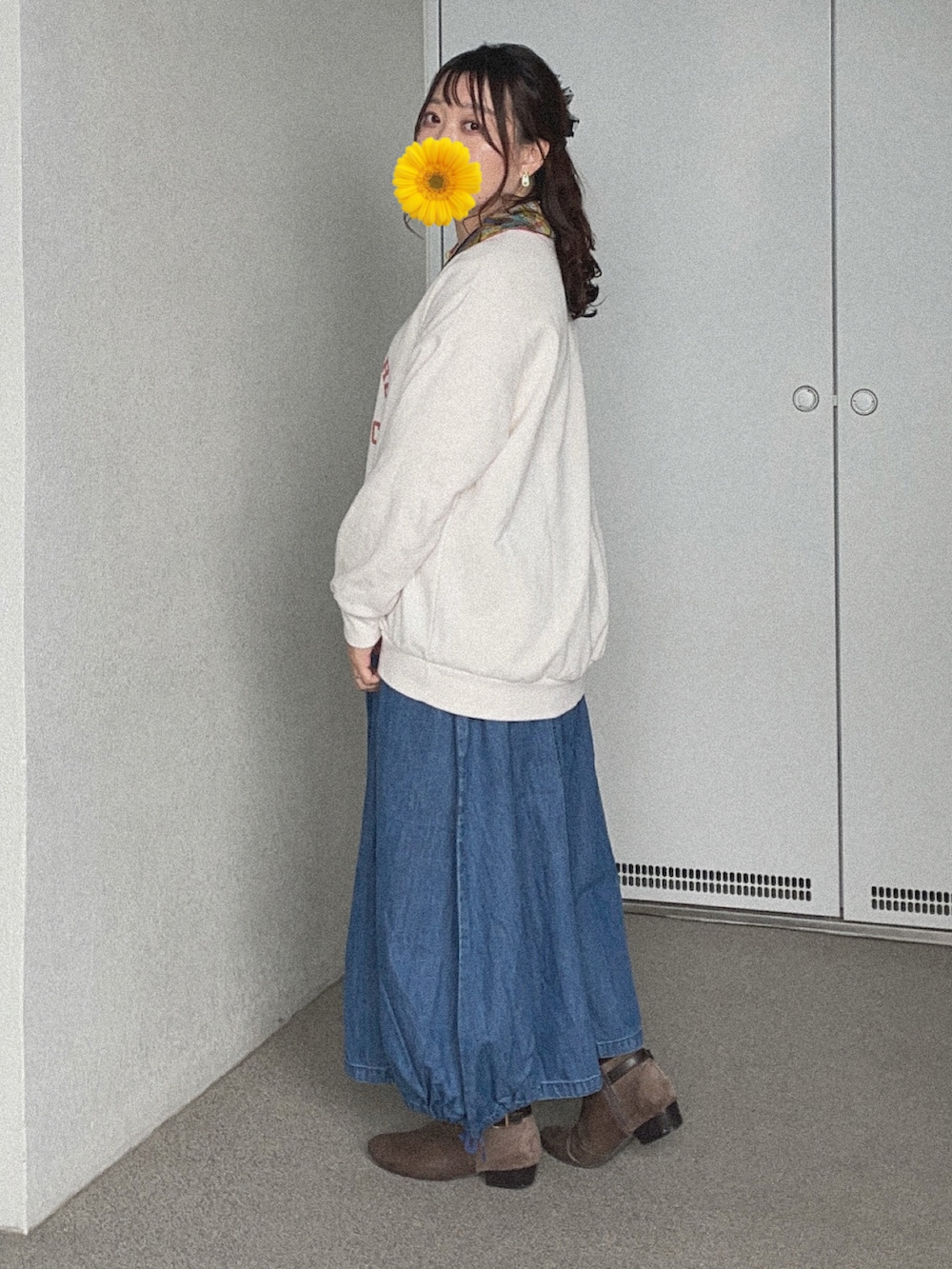 ホワイト系のスウェット、ブルー系のデニムスカート、グレー系のブーティを着用したレディースの冬コーディネートの2枚目の写真