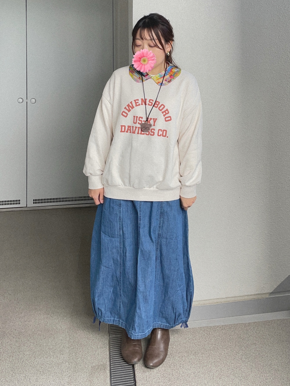 ホワイト系のスウェット、ブルー系のデニムスカート、グレー系のブーティを着用したレディースの冬コーディネートの3枚目の写真