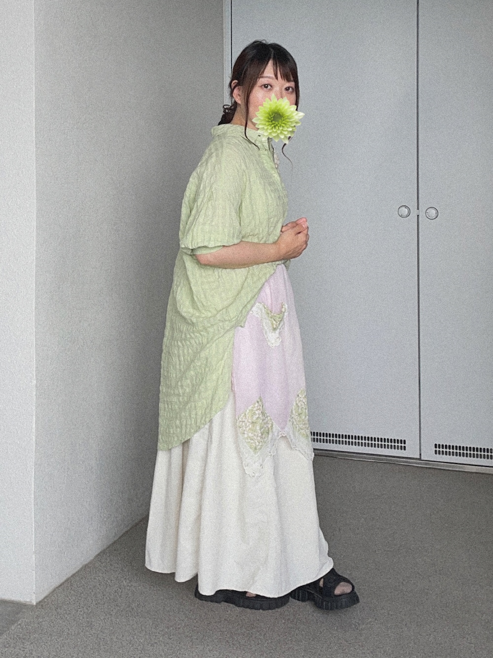 グリーン系のシャツ/ブラウス、ホワイト系のスカート、ブラック系のサンダルを着用したレディースの秋コーディネートの3枚目の写真