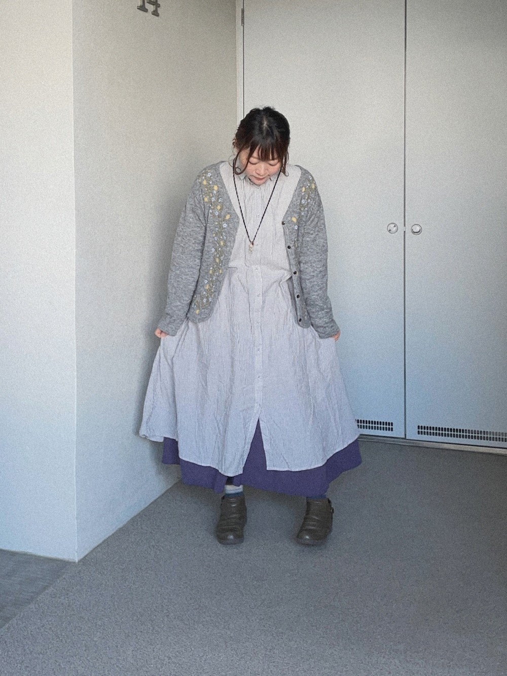 グレー系のシャツワンピース、パープル系のスカート、グレー系のニット/セーターを着用したレディースの春コーディネートの2枚目の写真
