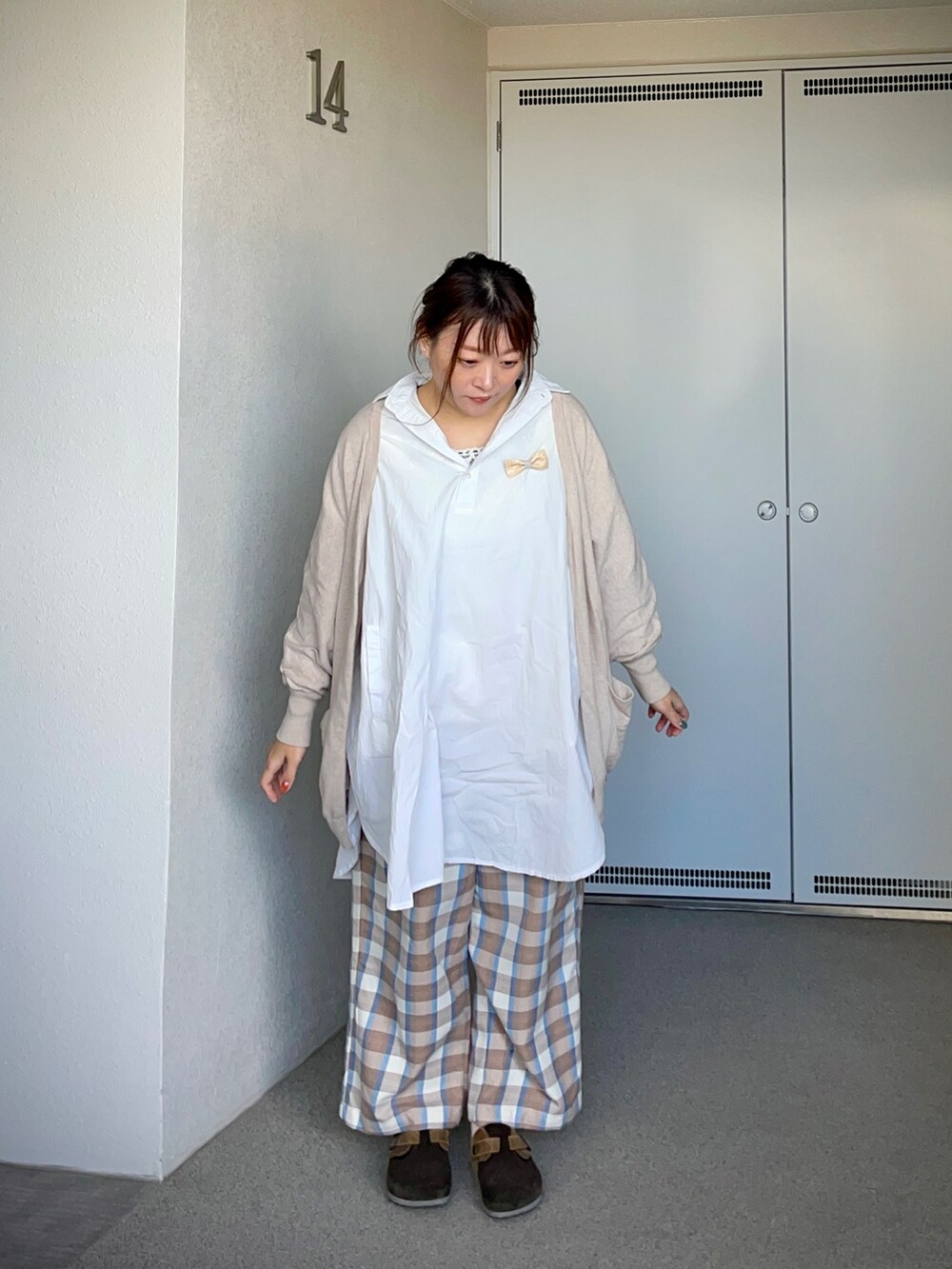 ベージュ系のスラックス、ホワイト系のシャツ/ブラウス、ベージュ系のカーディガン/ボレロを着用したレディースの冬コーディネートの2枚目の写真