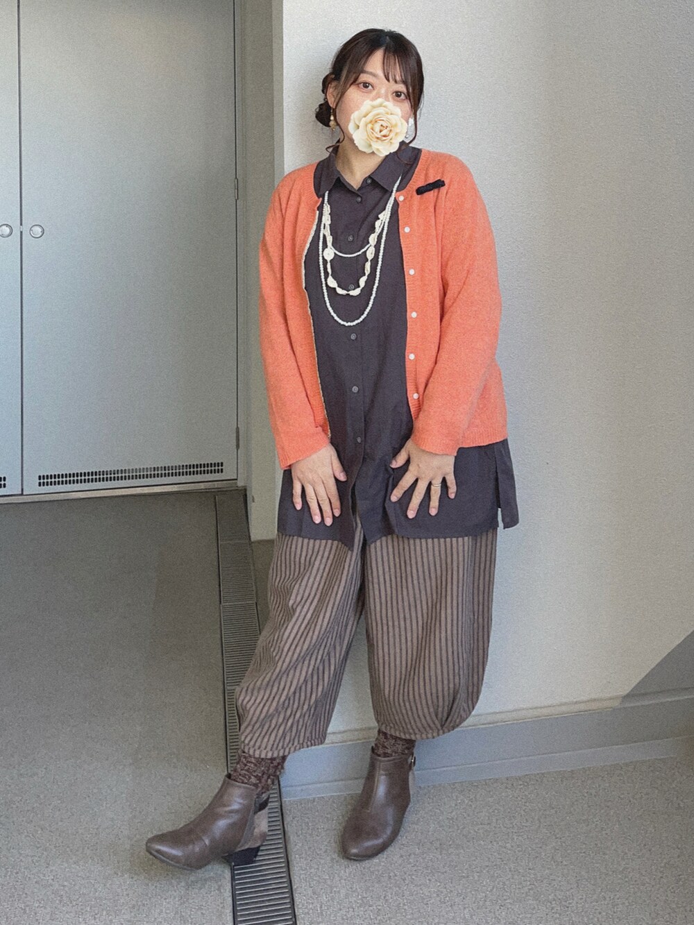 ブラック系のシャツ/ブラウス、オレンジ系のカーディガン/ボレロ、ブラウン系のチノパンツを着用したレディースの冬コーディネートの2枚目の写真