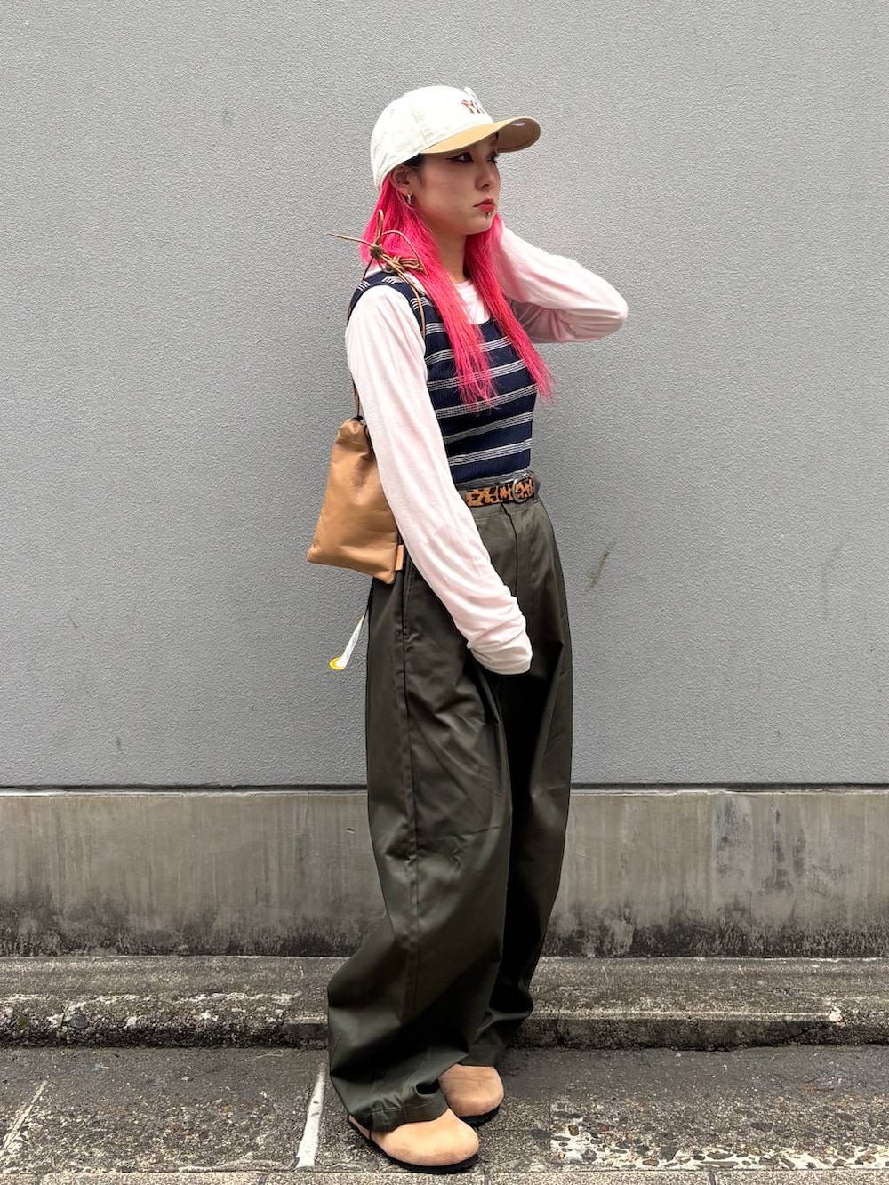 ベージュ系のショルダーバッグ、グリーン系のチノパンツ、ベージュ系のモカシン/デッキシューズを着用したレディースの春コーディネートの3枚目の写真