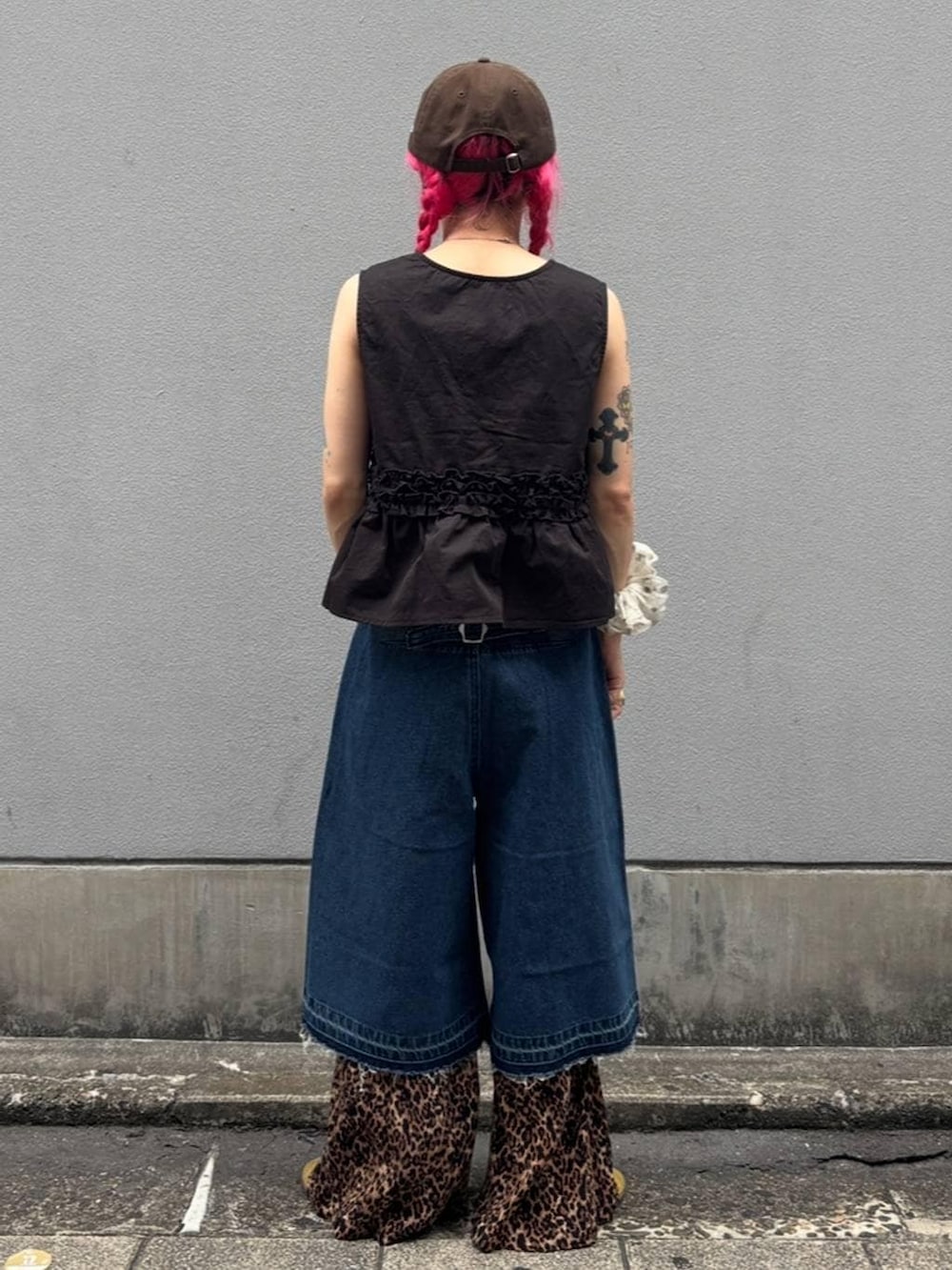 ブルー系のデニムパンツ、ブラック系のタンクトップ、ブラック系のベストを着用したレディースの夏コーディネートの4枚目の写真