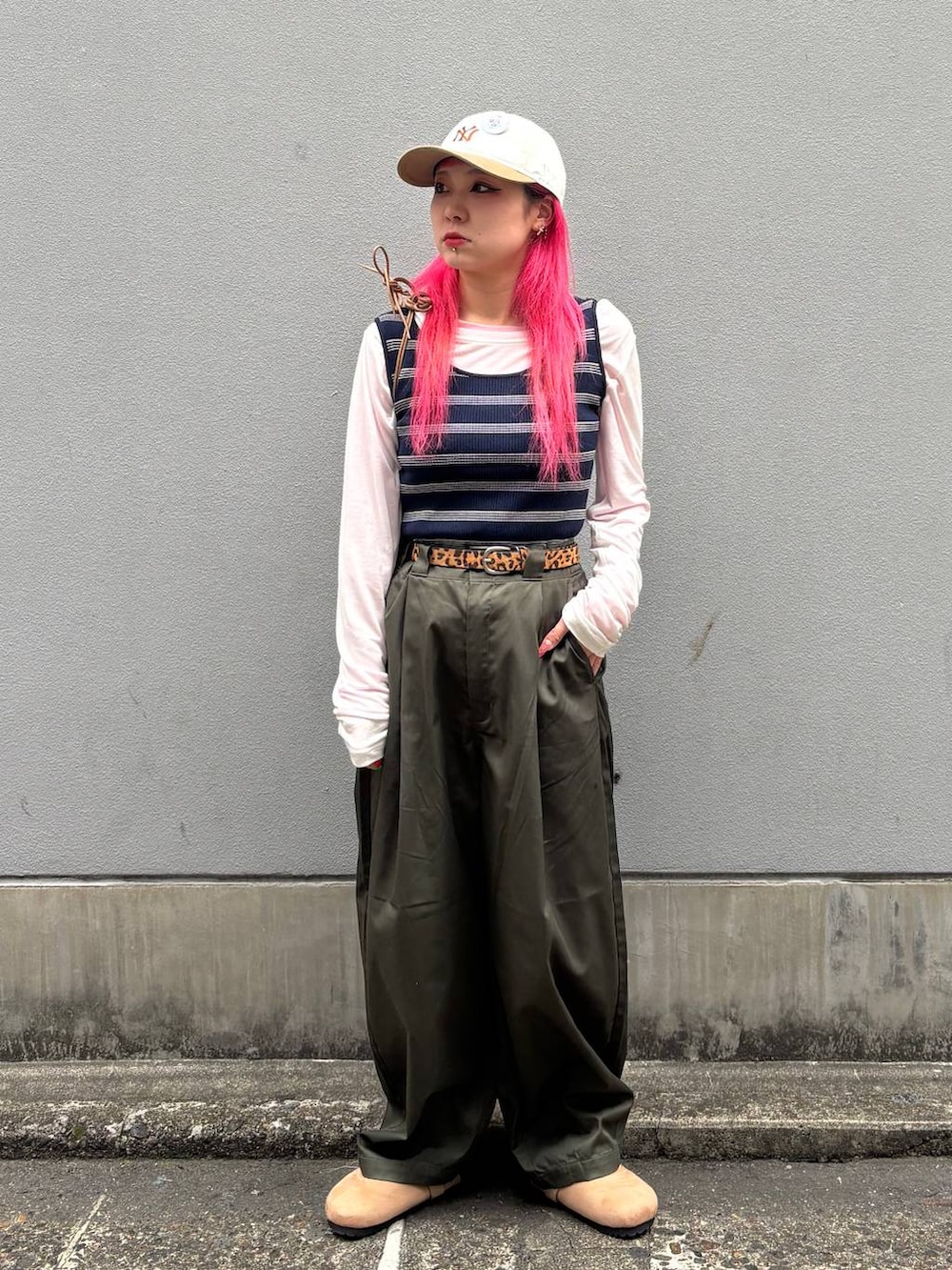 ベージュ系のショルダーバッグ、グリーン系のチノパンツ、ベージュ系のモカシン/デッキシューズを着用したレディースの春コーディネートの2枚目の写真