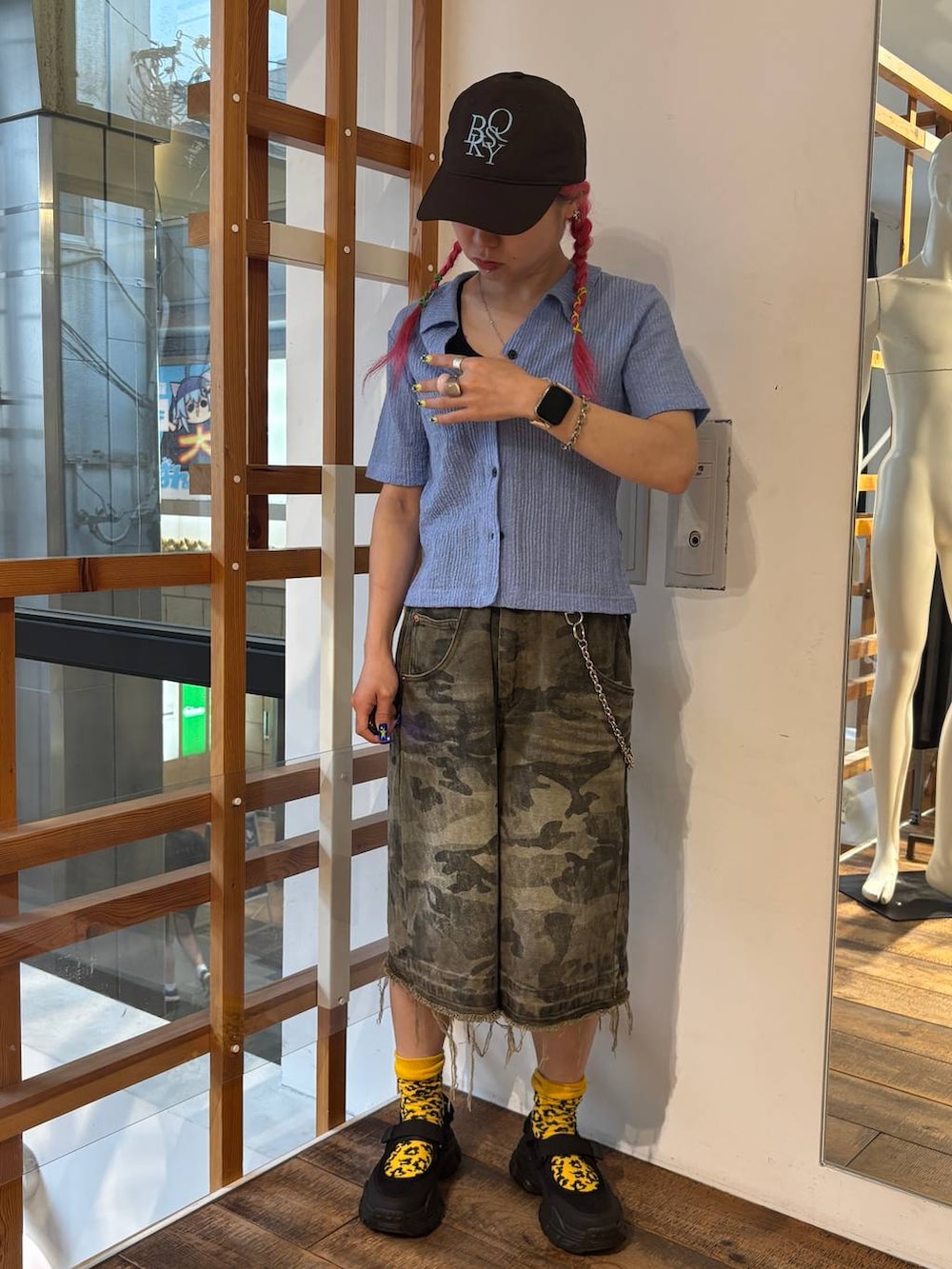 グリーン系のデニムパンツ、ブルー系のポロシャツ、ブラック系のタンクトップを着用したレディースの夏コーディネートの2枚目の写真