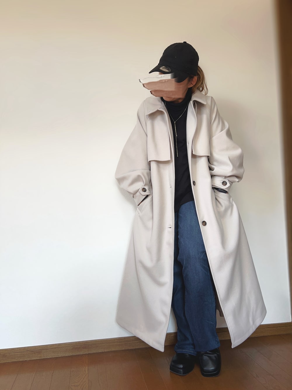 ブラック系のその他トップス、ホワイト系のチェスターコート、ブルー系のデニムパンツを着用したレディースの冬コーディネートの2枚目の写真