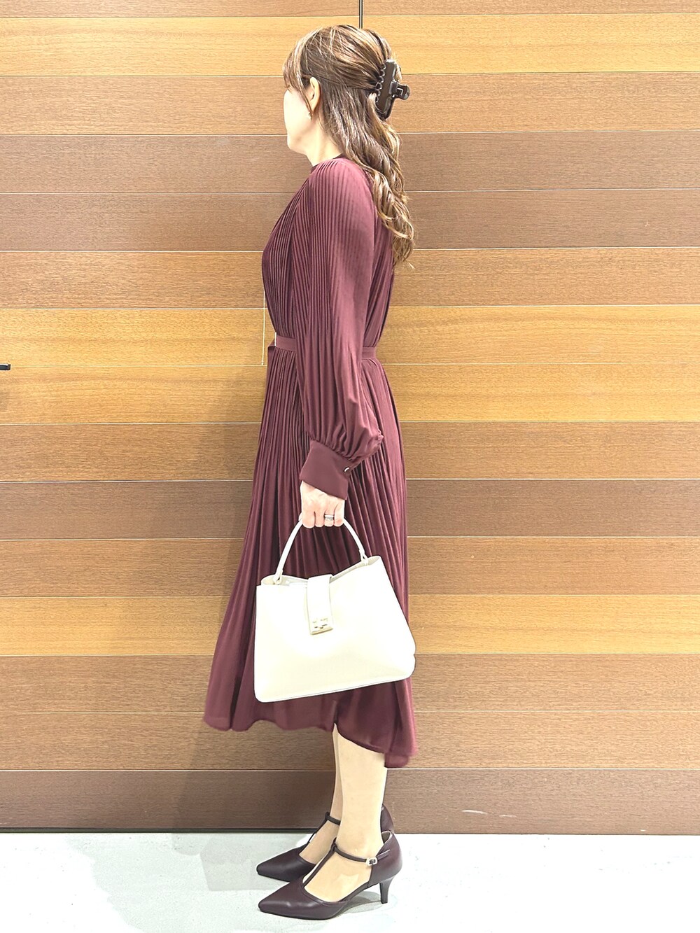 レッド系のワンピース、ホワイト系のハンドバッグ、レッド系のパンプスを着用したレディースの秋コーディネートの4枚目の写真