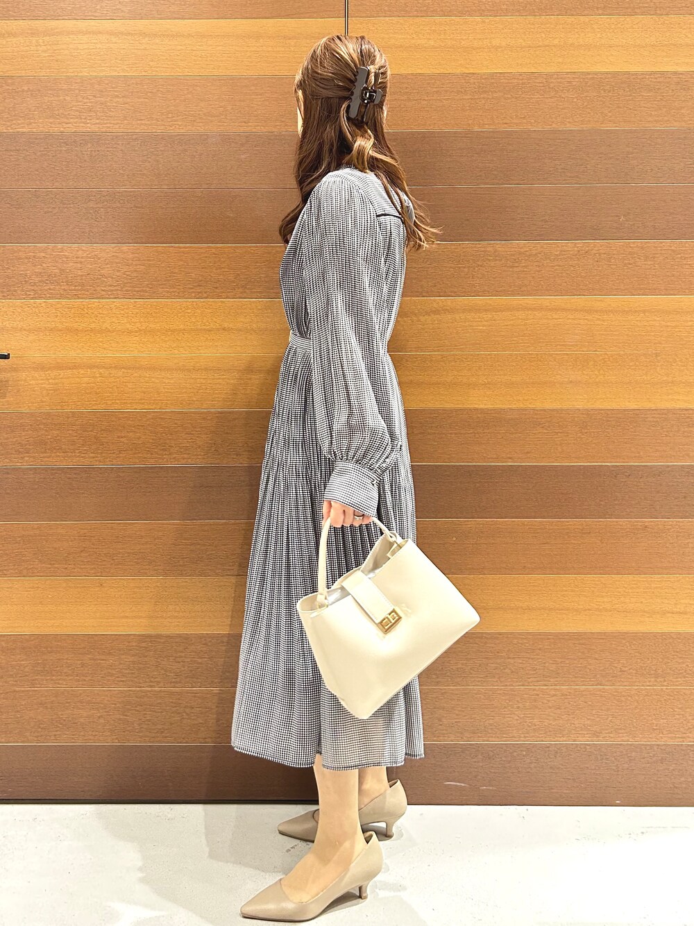 ブラック系のワンピース、ホワイト系のハンドバッグ、ベージュ系のパンプスを着用したレディースの秋コーディネートの4枚目の写真