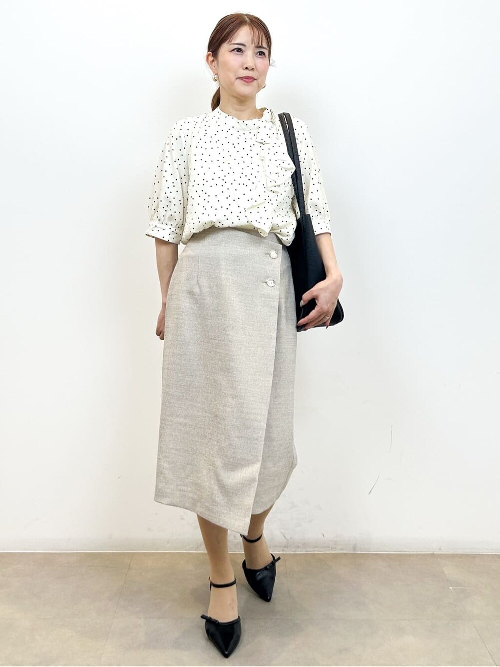 ベージュ系のシャツ/ブラウス、ベージュ系のスカート、ブラック系のトートバッグを着用したレディースの夏コーディネートの4枚目の写真