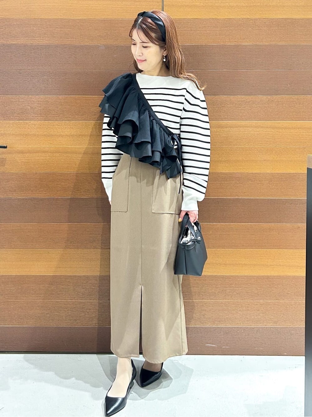 ブラック系のパンプス、ベージュ系のショルダーバッグ、ブラウン系のスカートを着用したレディースの春コーディネートの5枚目の写真