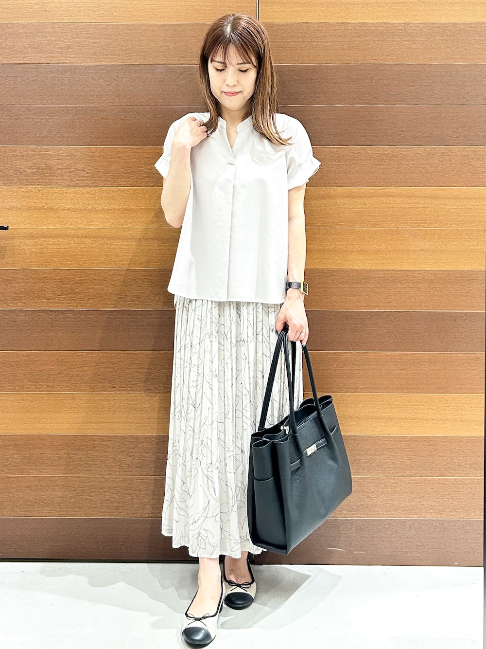 ベージュ系のシャツ/ブラウス、ブラック系のトートバッグ、ベージュ系のパンプスを着用したレディースの夏コーディネートの3枚目の写真