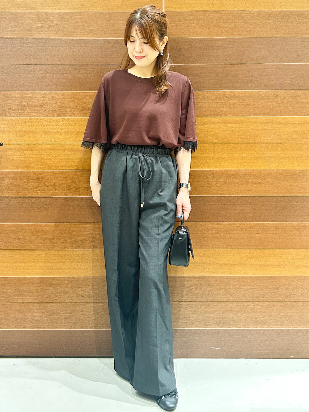 ブラウン系のニット/セーター、グレー系のその他パンツ、ブラック系のショルダーバッグを着用したレディースの夏コーディネートの3枚目の写真