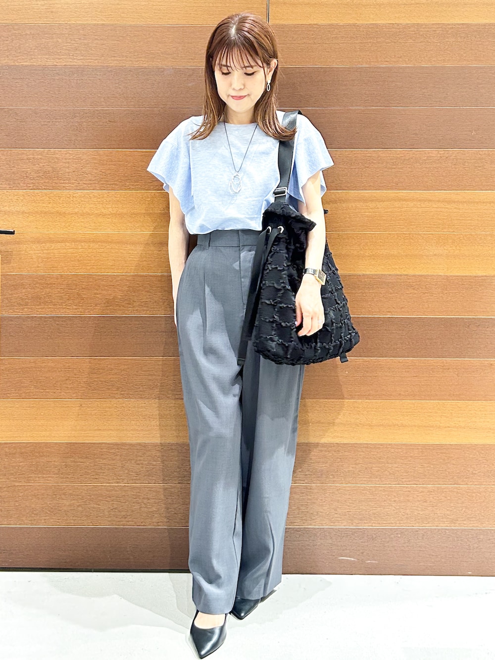 ブルー系のニット/セーター、グレー系のその他パンツ、ブラック系のトートバッグを着用したレディースの夏コーディネートの3枚目の写真