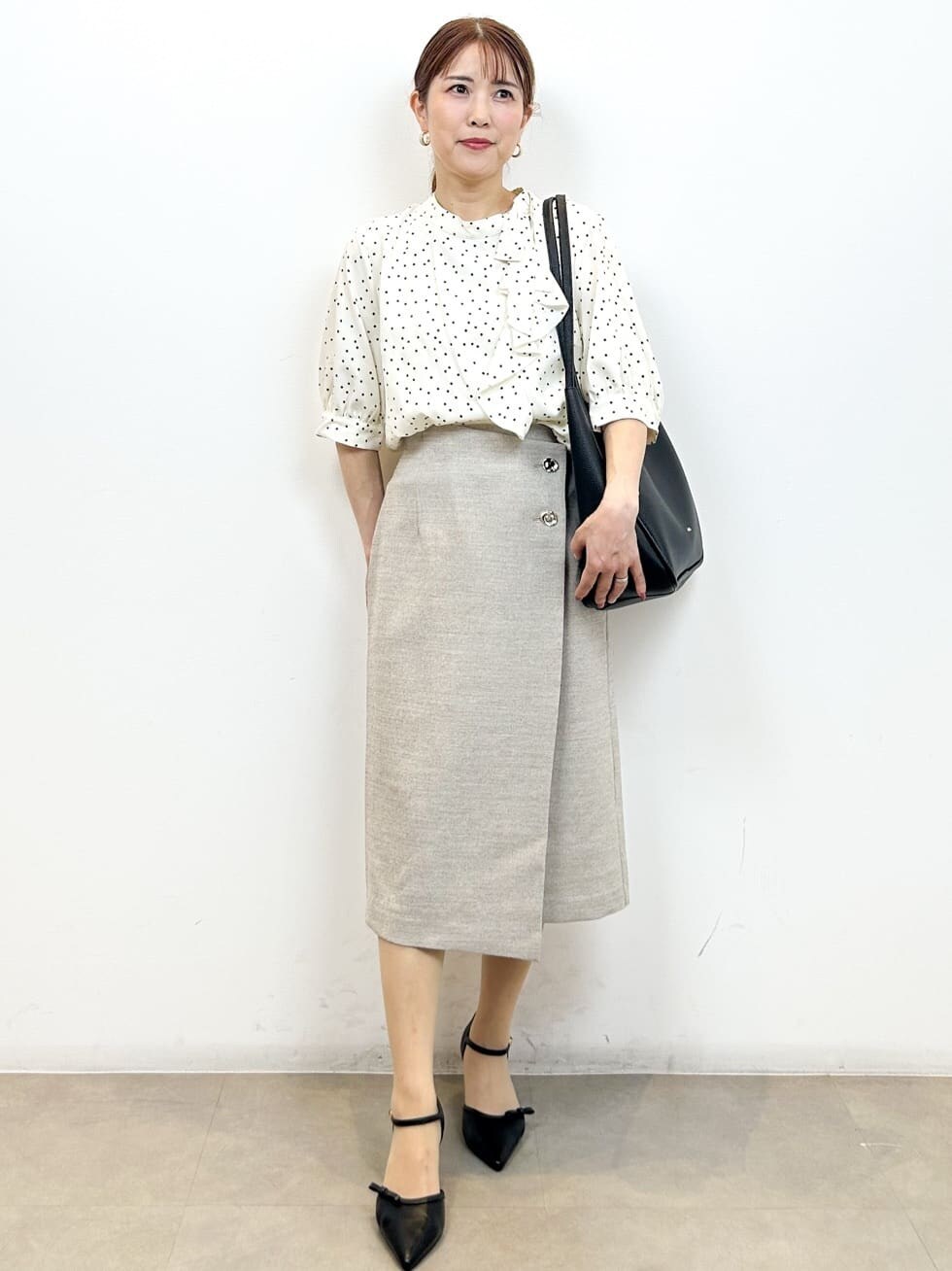 ベージュ系のシャツ/ブラウス、ベージュ系のスカート、ブラック系のトートバッグを着用したレディースの夏コーディネートの6枚目の写真