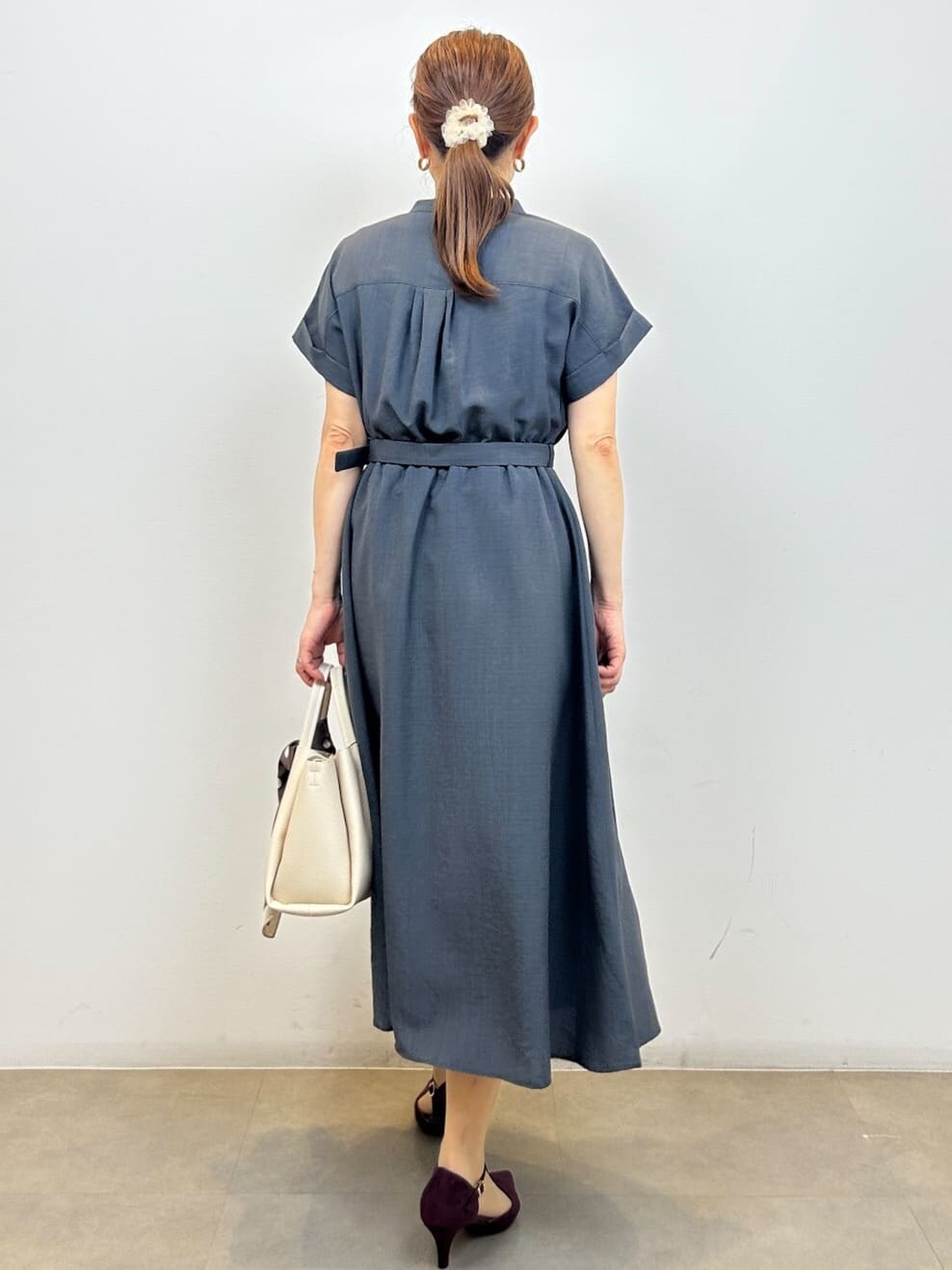 グレー系のワンピース、ホワイト系のショルダーバッグ、レッド系のパンプスを着用したレディースの夏コーディネートの5枚目の写真