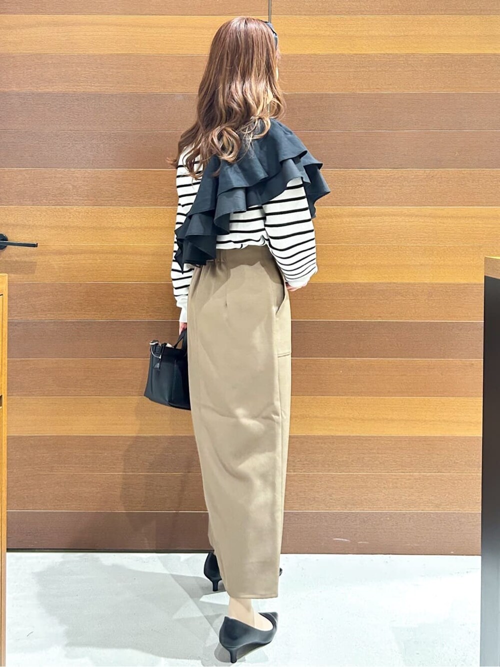 ブラック系のパンプス、ベージュ系のショルダーバッグ、ブラウン系のスカートを着用したレディースの春コーディネートの9枚目の写真