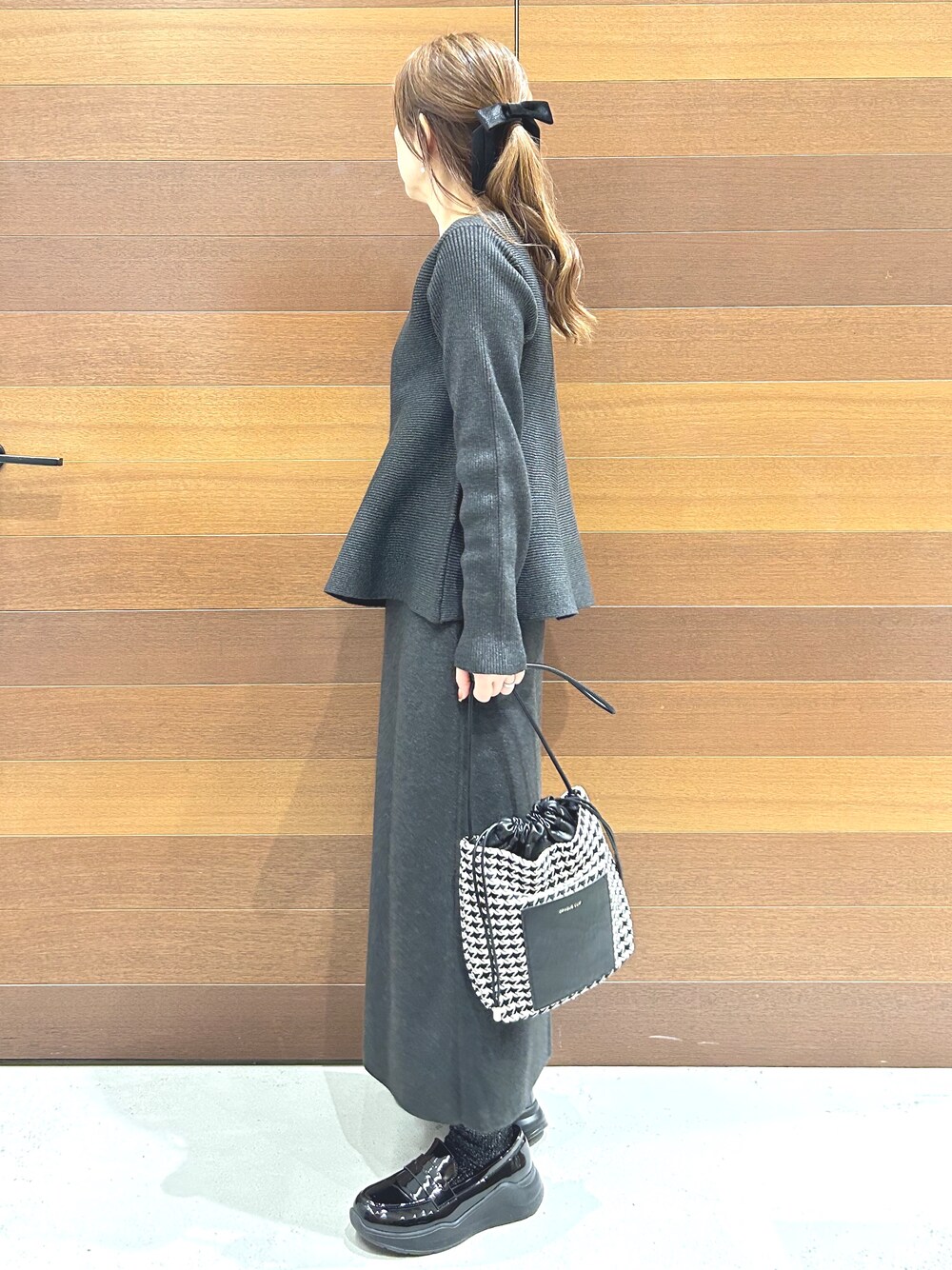 グレー系のニット/セーター、グレー系のスカート、ブラック系のショルダーバッグを着用したレディースの秋コーディネートの5枚目の写真