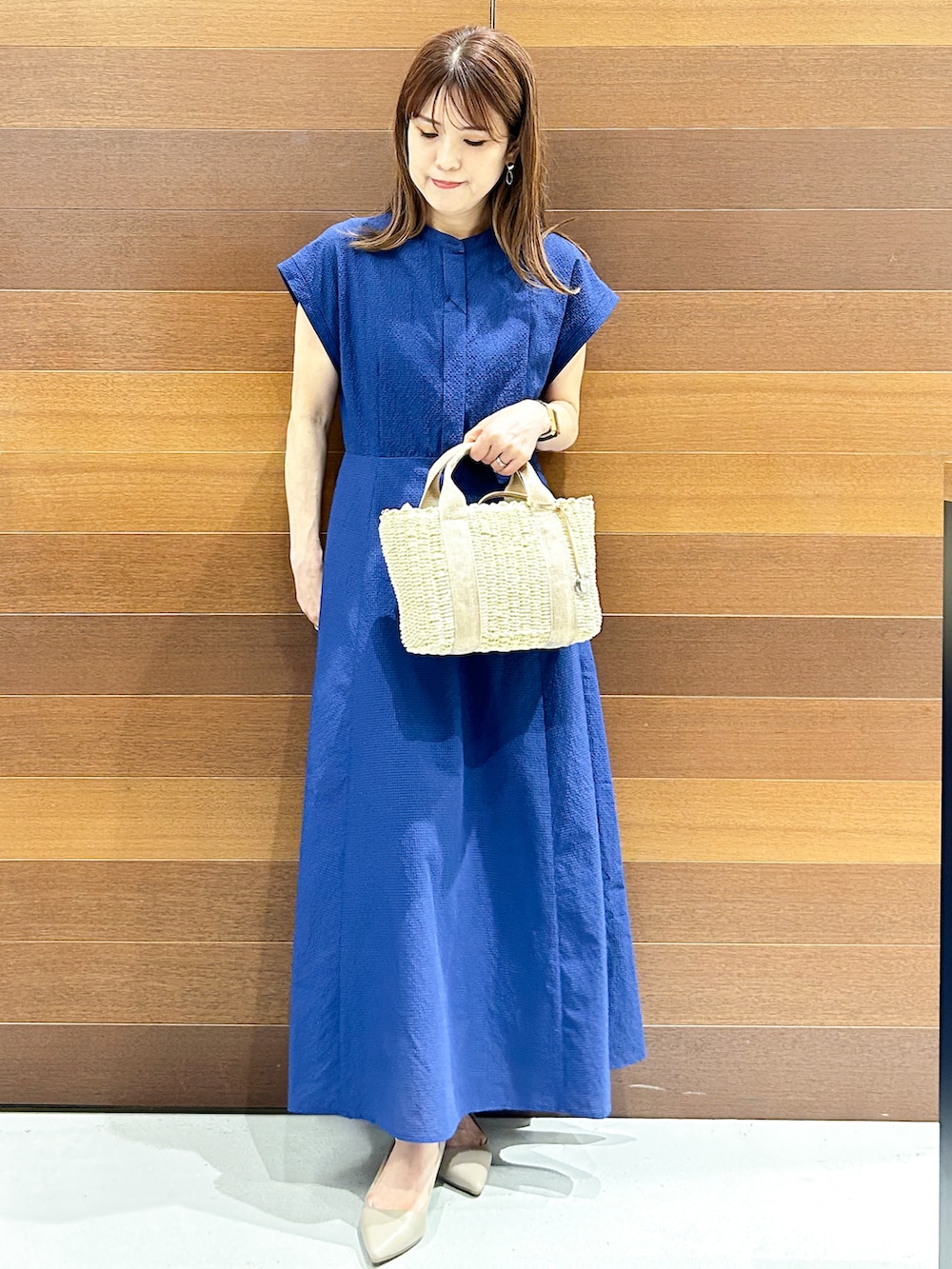 ブルー系のワンピース、ベージュ系のトートバッグ、ベージュ系のパンプスを着用したレディースの夏コーディネートの2枚目の写真