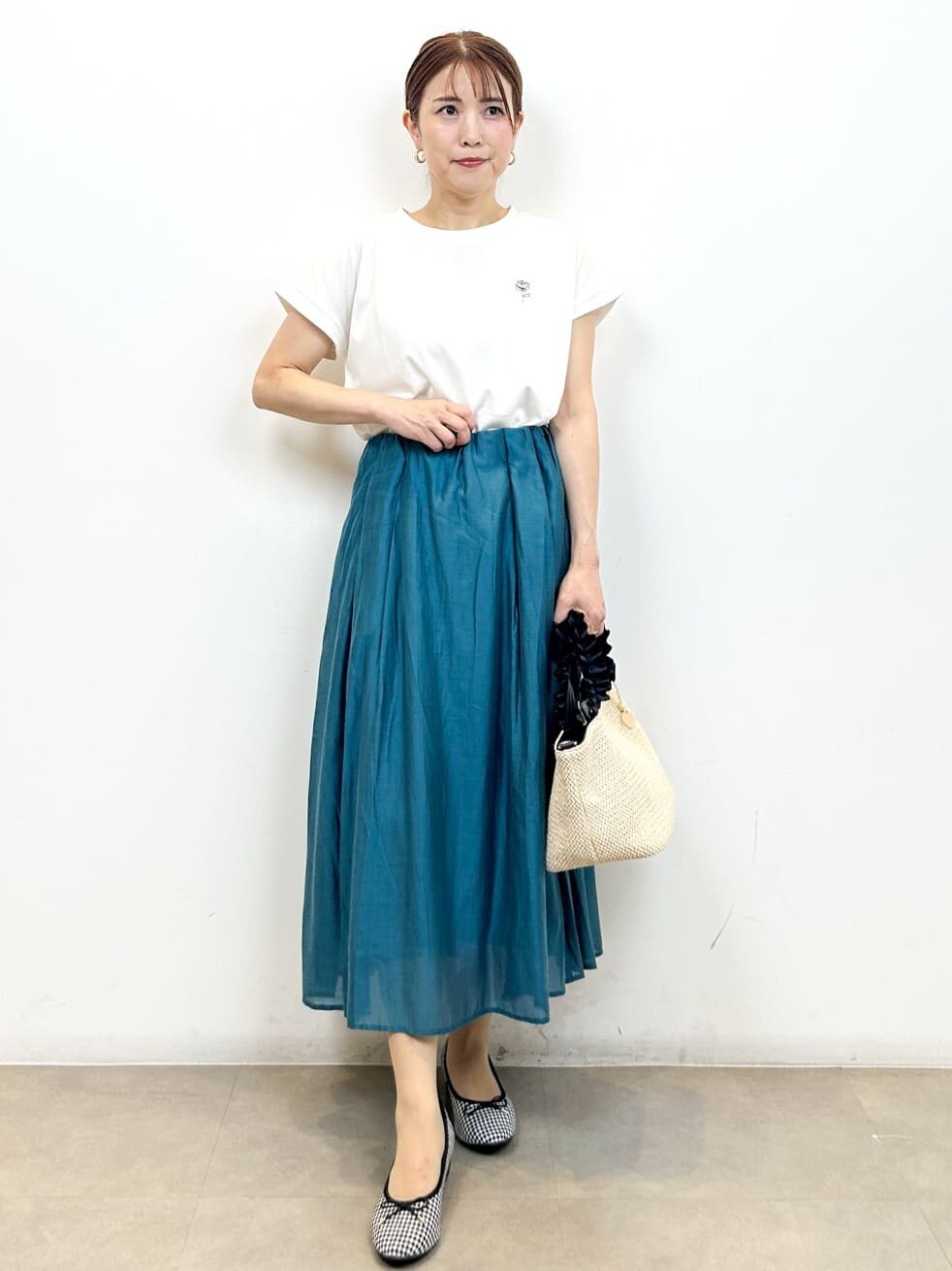 ホワイト系のTシャツ/カットソー、ブルー系のスカート、ブラック系のトートバッグを着用したレディースの夏コーディネートの6枚目の写真