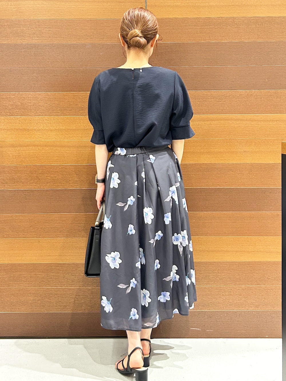 ブルー系のシャツ/ブラウス、グレー系のスカート、ブラック系のトートバッグを着用したレディースの夏コーディネートの6枚目の写真