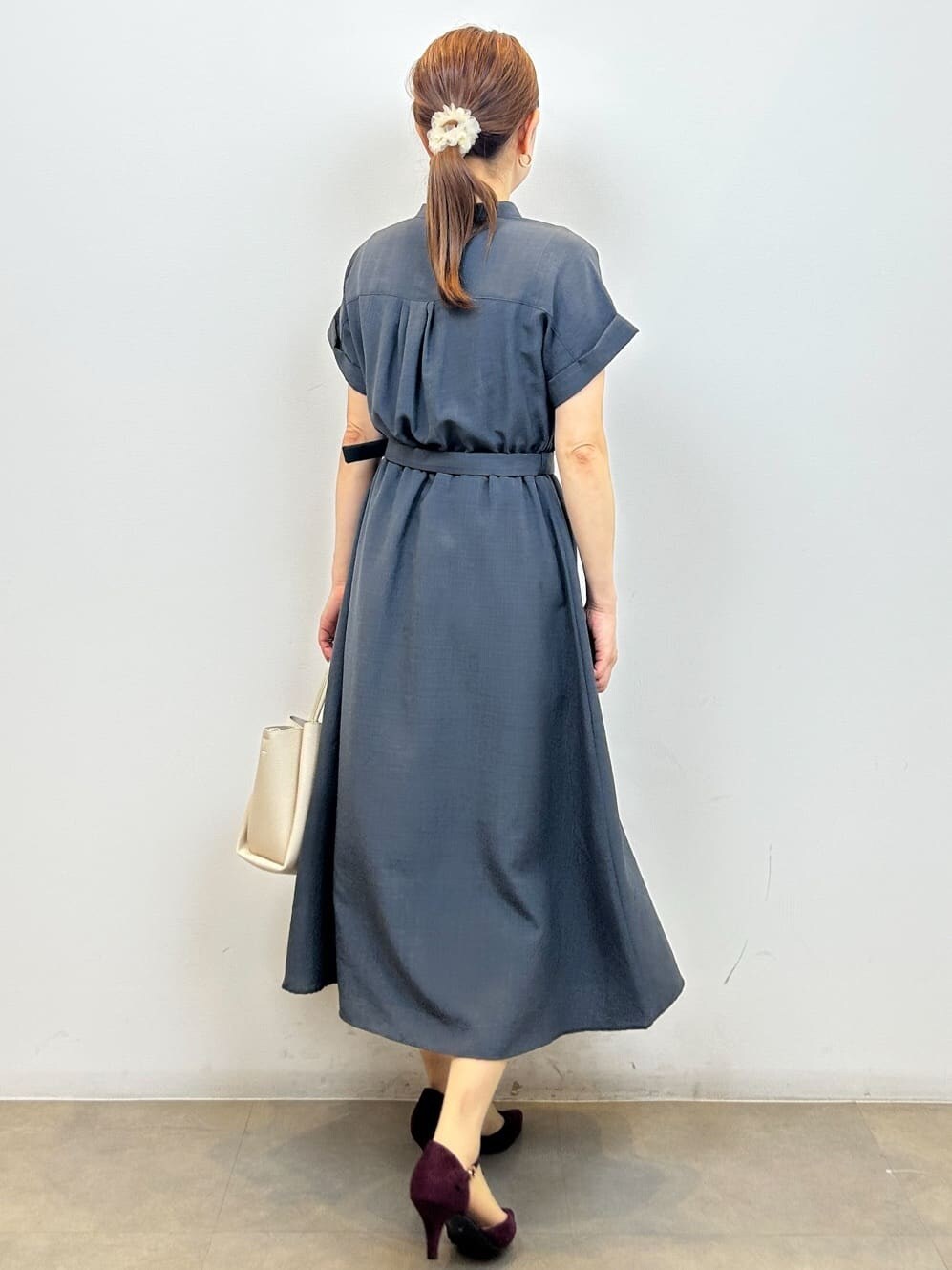 グレー系のワンピース、ホワイト系のショルダーバッグ、レッド系のパンプスを着用したレディースの夏コーディネートの6枚目の写真