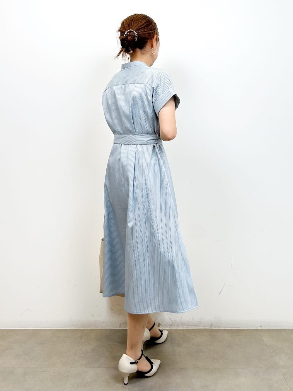 ブルー系のワンピース、ホワイト系のトートバッグ、ホワイト系のパンプスを着用したレディースの夏コーディネートの6枚目の写真