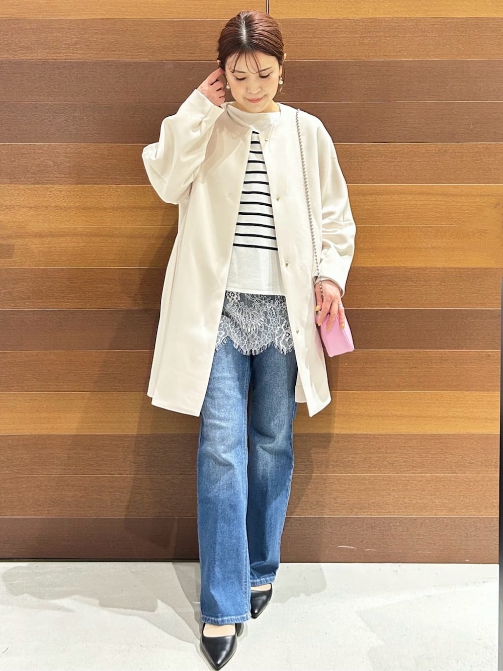ブルー系のデニムパンツ、ホワイト系のノーカラーコート、ブラック系のショルダーバッグを着用したレディースの春コーディネートの7枚目の写真
