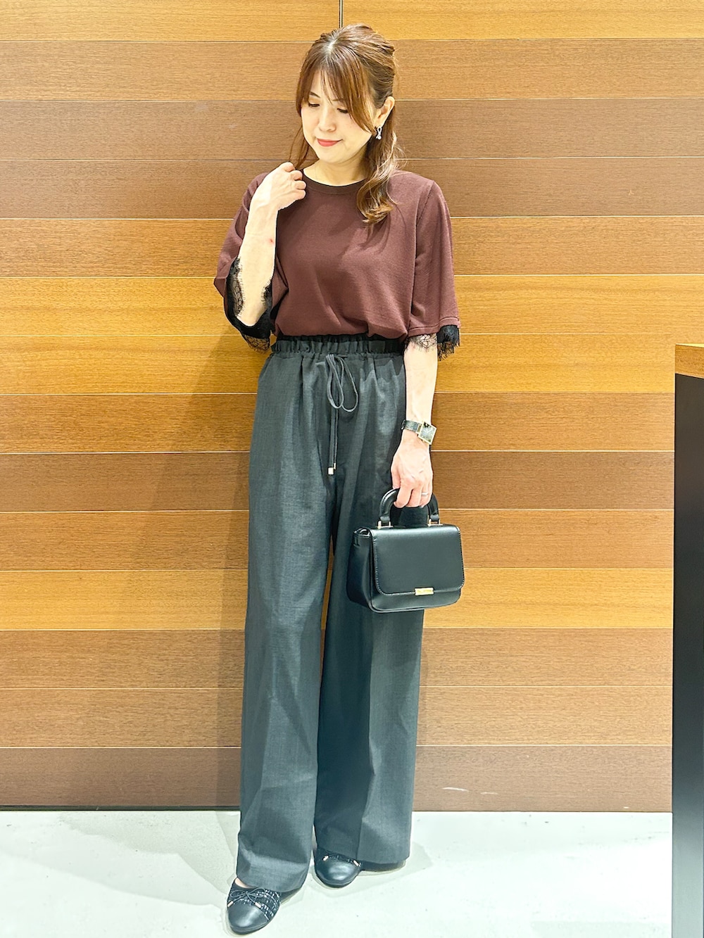 ブラウン系のニット/セーター、グレー系のその他パンツ、ブラック系のショルダーバッグを着用したレディースの夏コーディネートの2枚目の写真