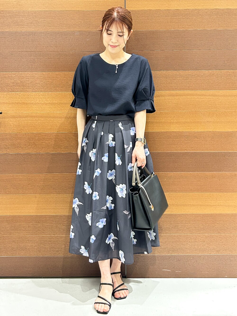 ブルー系のシャツ/ブラウス、グレー系のスカート、ブラック系のトートバッグを着用したレディースの夏コーディネートの2枚目の写真