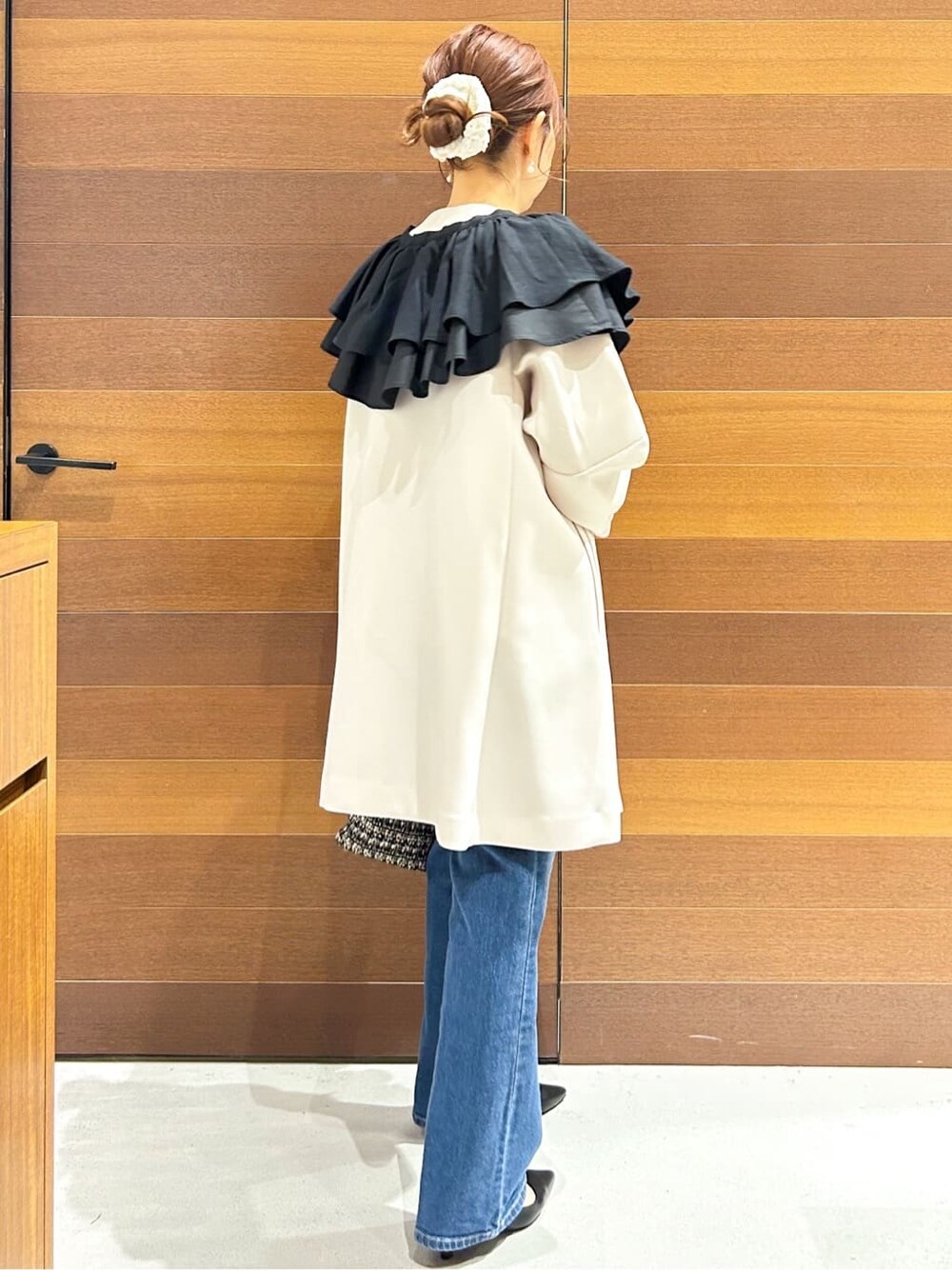 ブルー系のデニムパンツ、ホワイト系のノーカラーコート、ブラック系のショルダーバッグを着用したレディースの春コーディネートの6枚目の写真