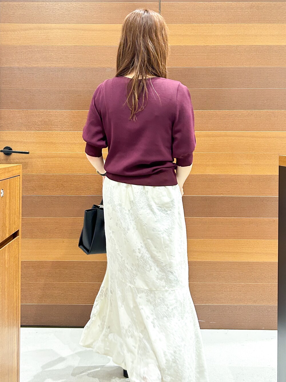 ホワイト系のスカート、ブラック系のトートバッグ、ベージュ系のパンプスを着用したレディースの夏コーディネートの6枚目の写真