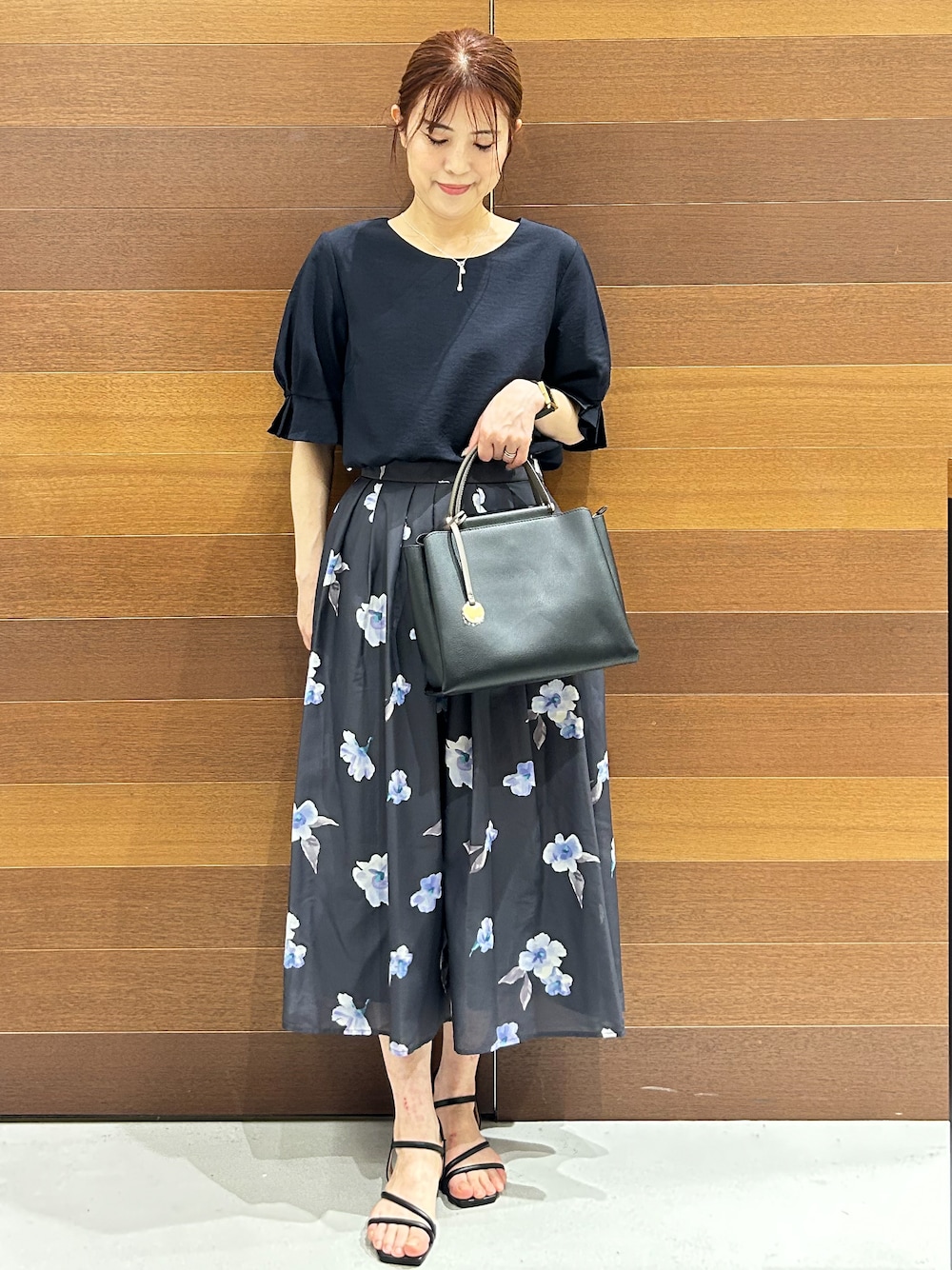 ブルー系のシャツ/ブラウス、グレー系のスカート、ブラック系のトートバッグを着用したレディースの夏コーディネートの7枚目の写真