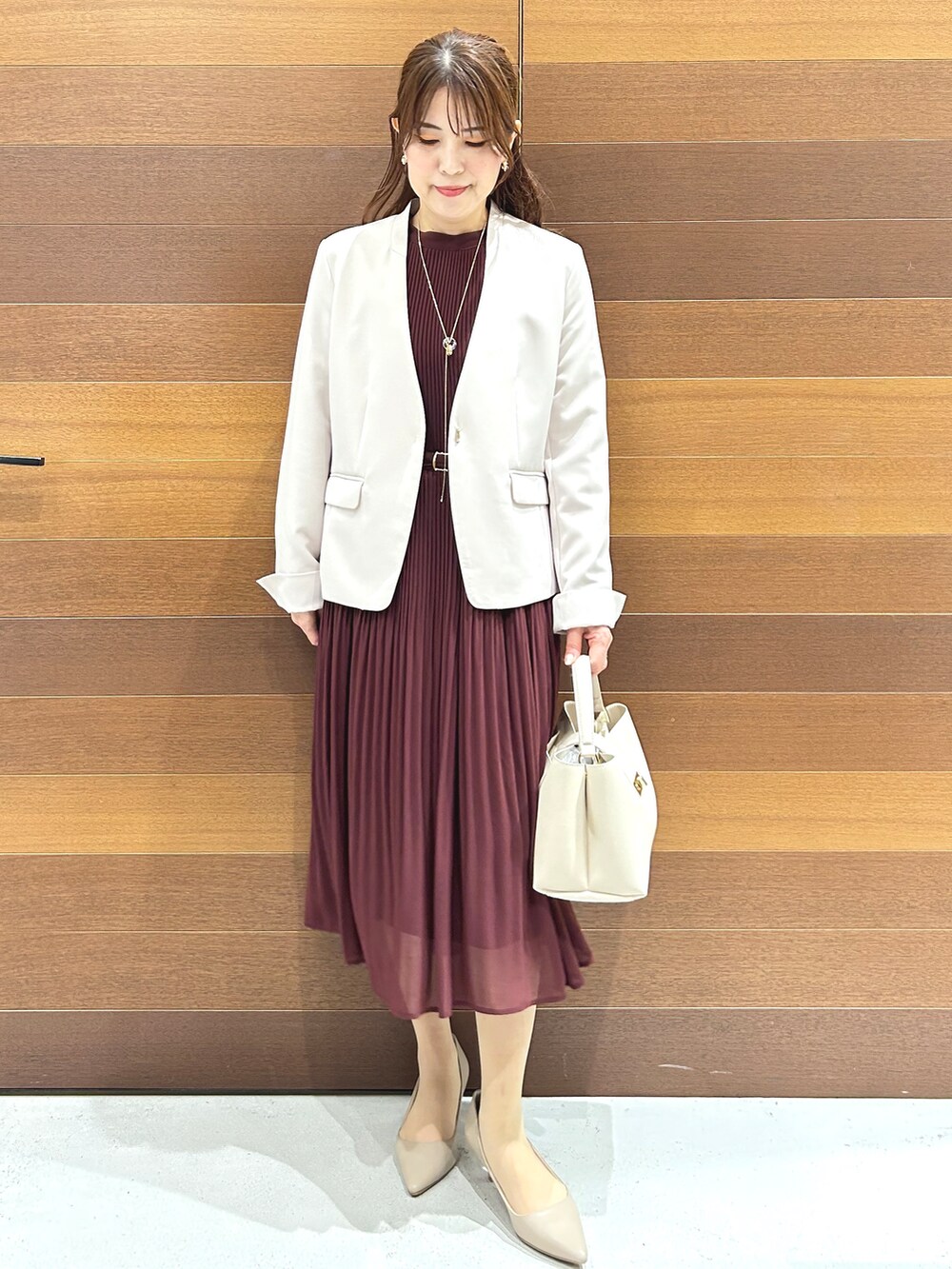 ベージュ系のノーカラージャケット、レッド系のワンピース、ホワイト系のハンドバッグを着用したレディースの秋コーディネートの2枚目の写真