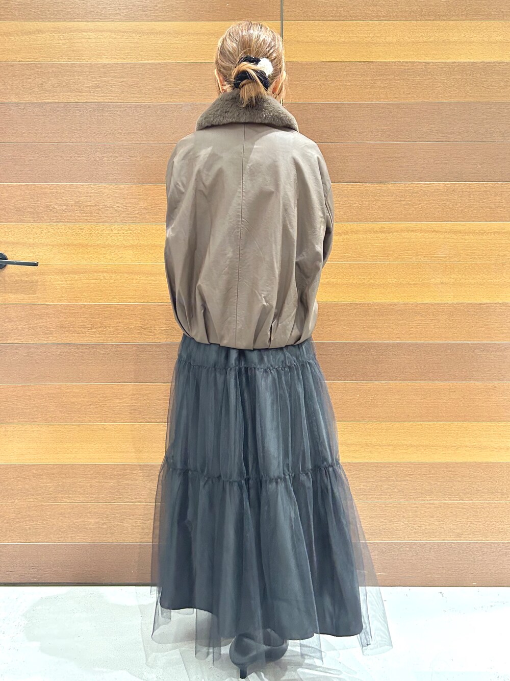 ブラウン系のブルゾン、ホワイト系のTシャツ/カットソー、ブラック系のスカートを着用したレディースの秋コーディネートの6枚目の写真
