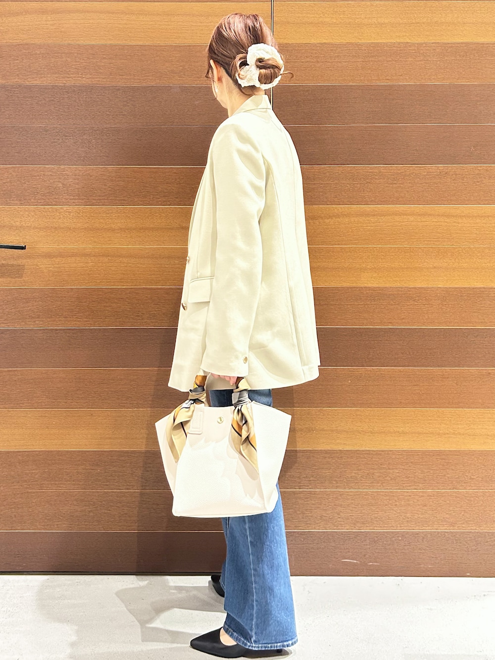 ブルー系のデニムパンツ、ホワイト系のショルダーバッグ、ブラック系のパンプスを着用したレディースの春コーディネートの5枚目の写真