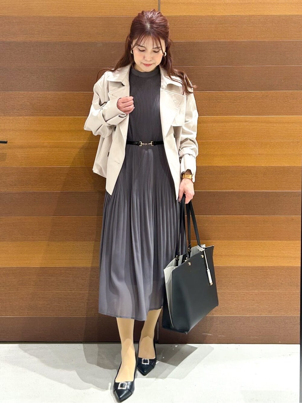 ベージュ系のトレンチコート、グレー系のワンピース、ブラック系のトートバッグを着用したレディースの春コーディネートの3枚目の写真