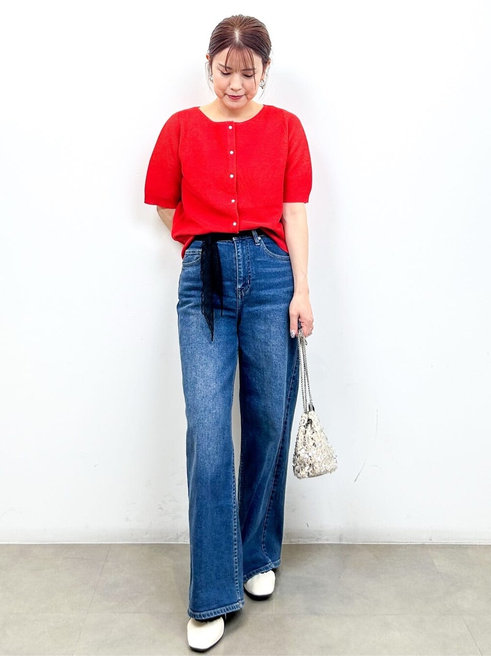 レッド系のカーディガン/ボレロ、ブルー系のデニムパンツ、ホワイト系のショルダーバッグを着用したレディースの夏コーディネートの3枚目の写真