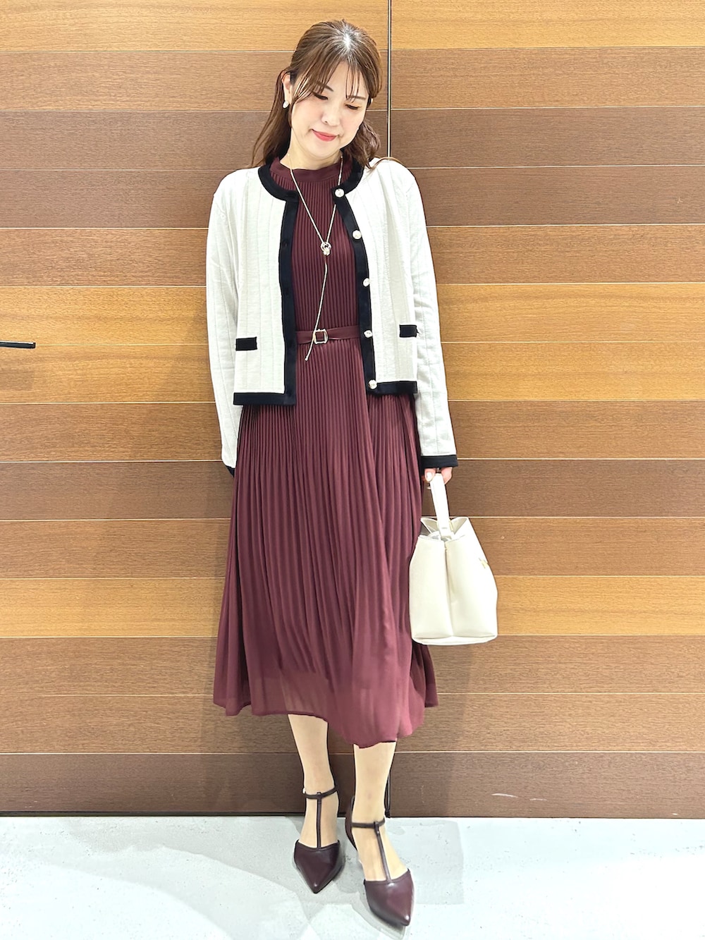 ベージュ系のノーカラージャケット、レッド系のワンピース、ホワイト系のハンドバッグを着用したレディースの秋コーディネートの3枚目の写真