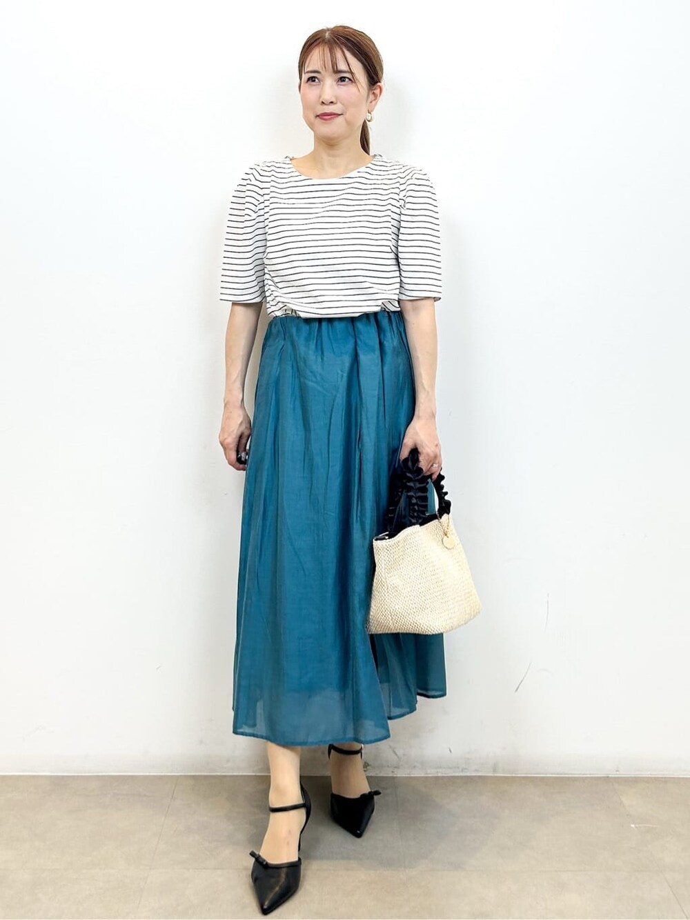 ホワイト系のTシャツ/カットソー、ブルー系のスカート、ブラック系のトートバッグを着用したレディースの夏コーディネートの6枚目の写真