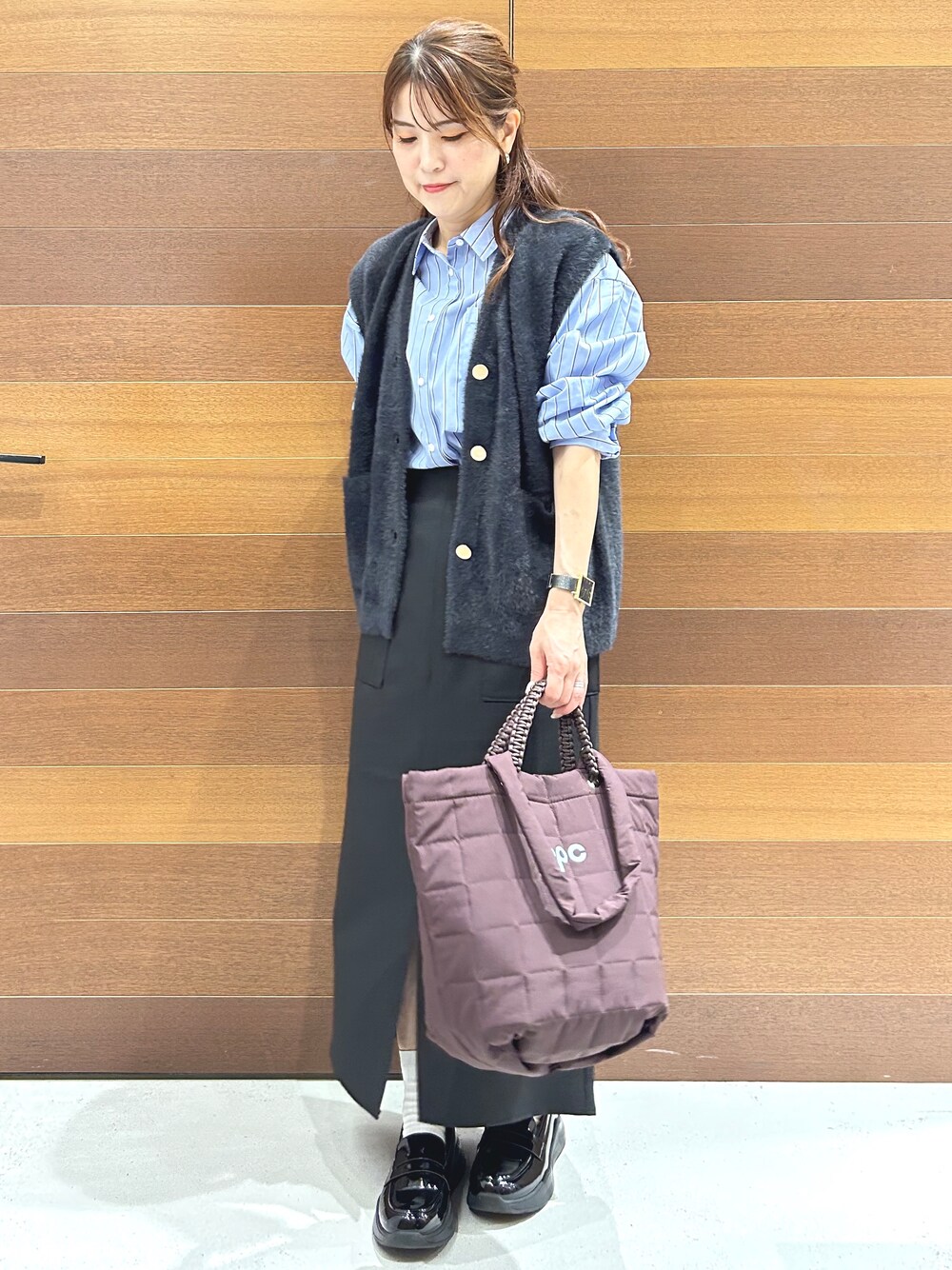 グレー系のニット/セーター、ブルー系のシャツ/ブラウス、ブラック系のスカートを着用したレディースの秋コーディネートの3枚目の写真