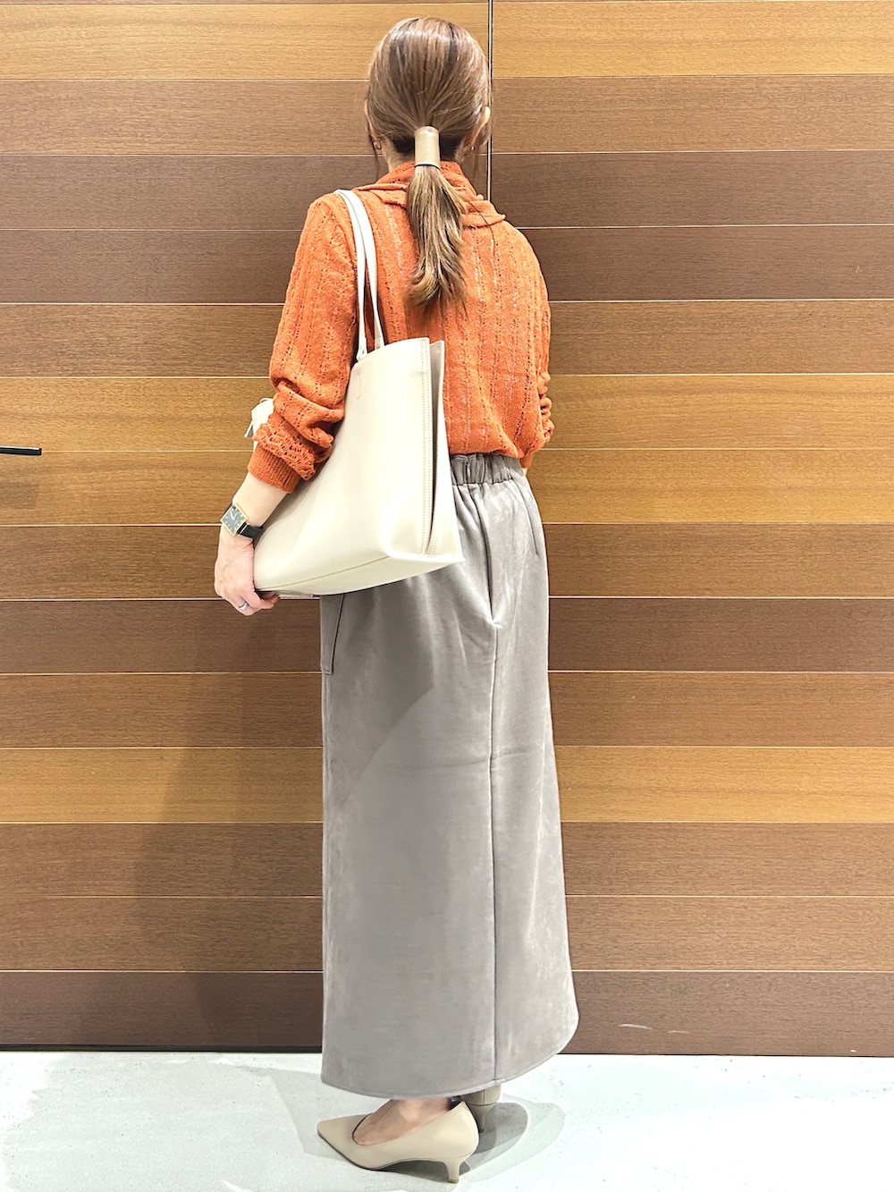オレンジ系のカーディガン/ボレロ、ベージュ系のトートバッグ、ベージュ系のパンプスを着用したレディースの秋コーディネートの4枚目の写真